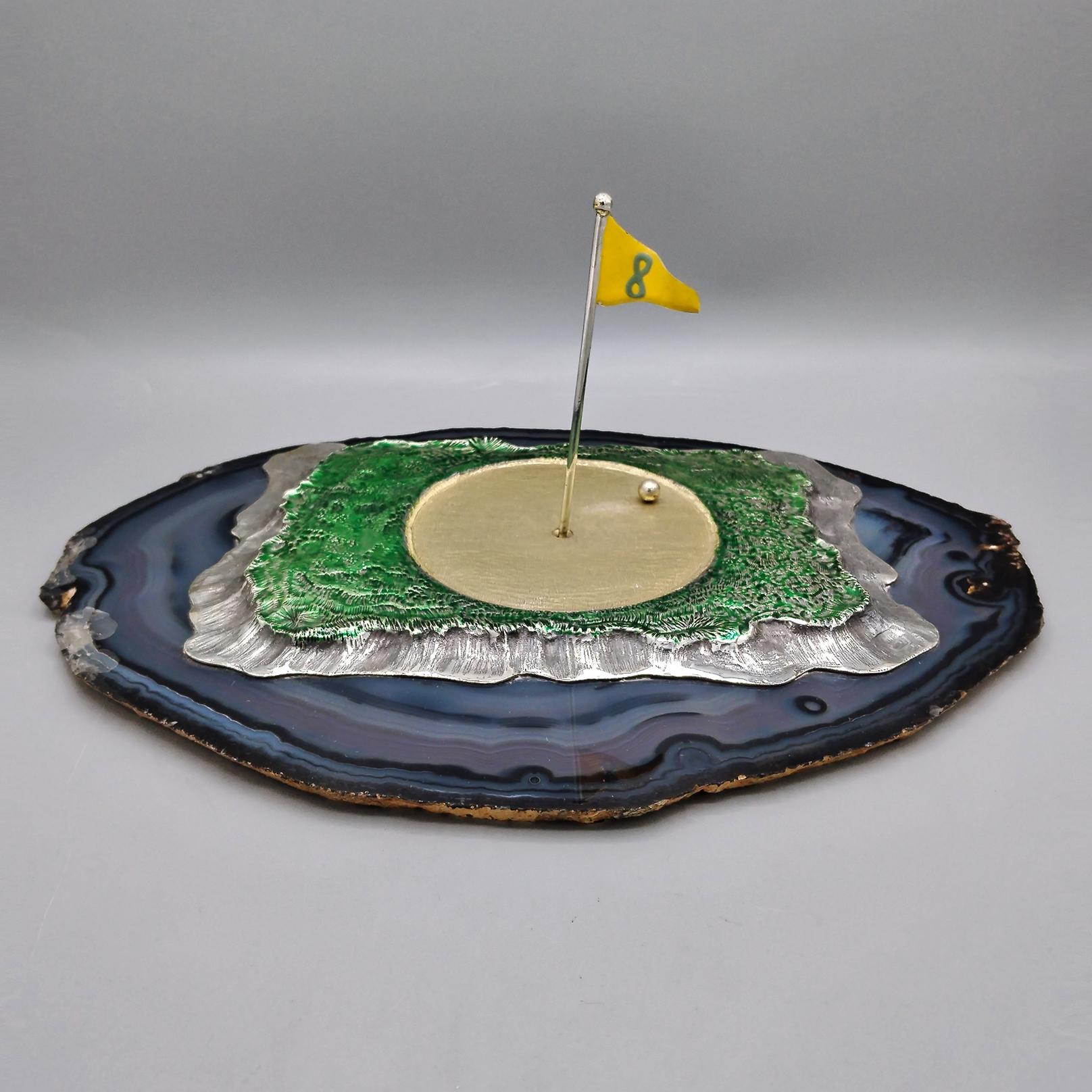 Vert de golf en argent massif 800 émaillé, bruni et doré sur une base en agate

Fabriqué à partir d'une feuille d'argent brut d'environ 300 grammes, ce green de golf a été modelé et façonné entièrement à la main.
Le bord est dentelé, tandis que la