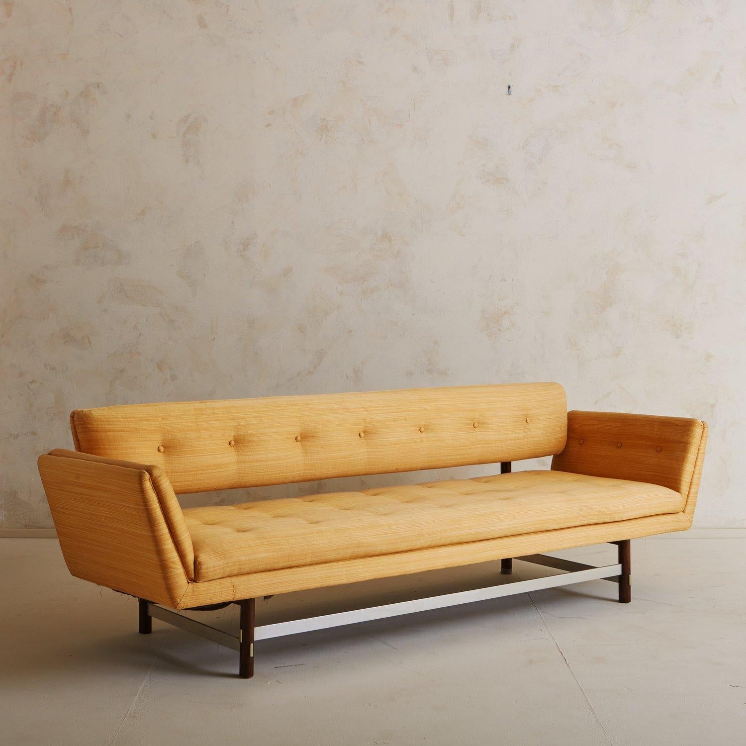A Gondola sofa designed by Edward Wormley for Dunbar’s Janus Collection in the 1950s. This sculptural sofa features angled arms and a floating back attached to the base with walnut supports and brass hardware. It has four cylindrical walnut legs