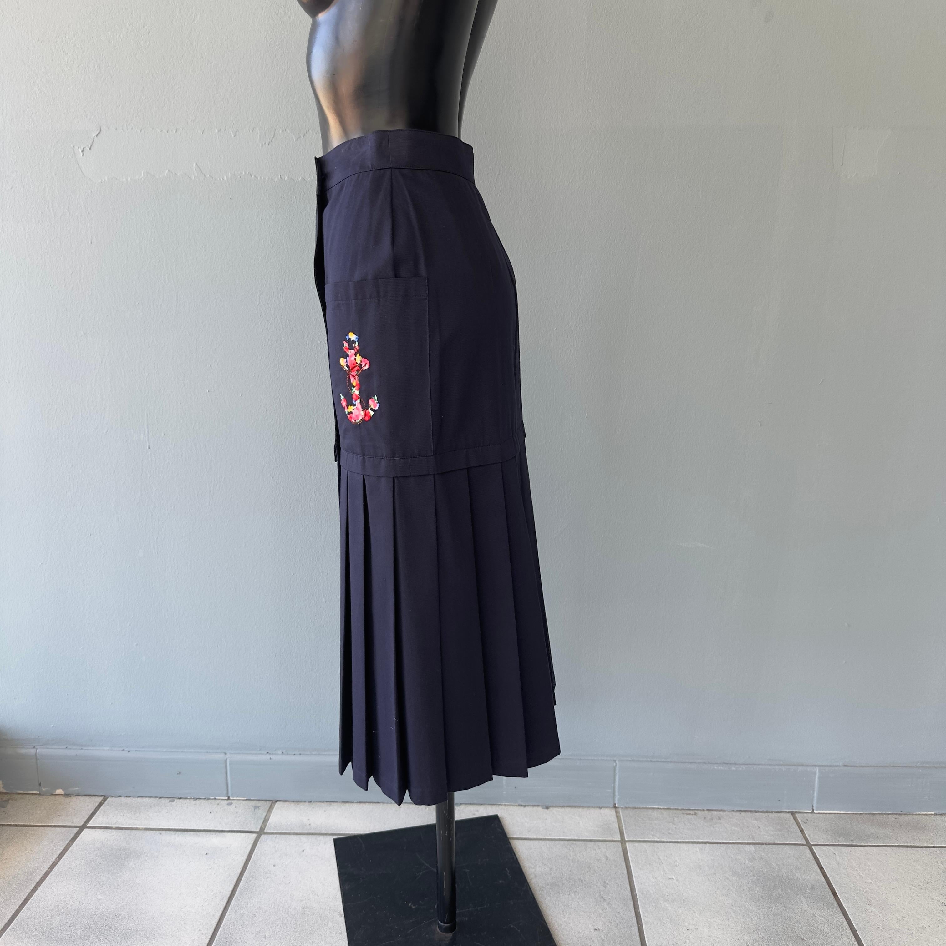 Gonna blu navi Les Copains a portafogli con tasche laterali. Parte sopra lisci ed a pieghe sotto. Grande ancora di fiori ricamata su una tasca. Anni 80/90 nuova mai utilizzata 
Composizione cotone
Taglia I 
Misure: 
Vita 33cm 
Fianchi 41cm
Lunghezza