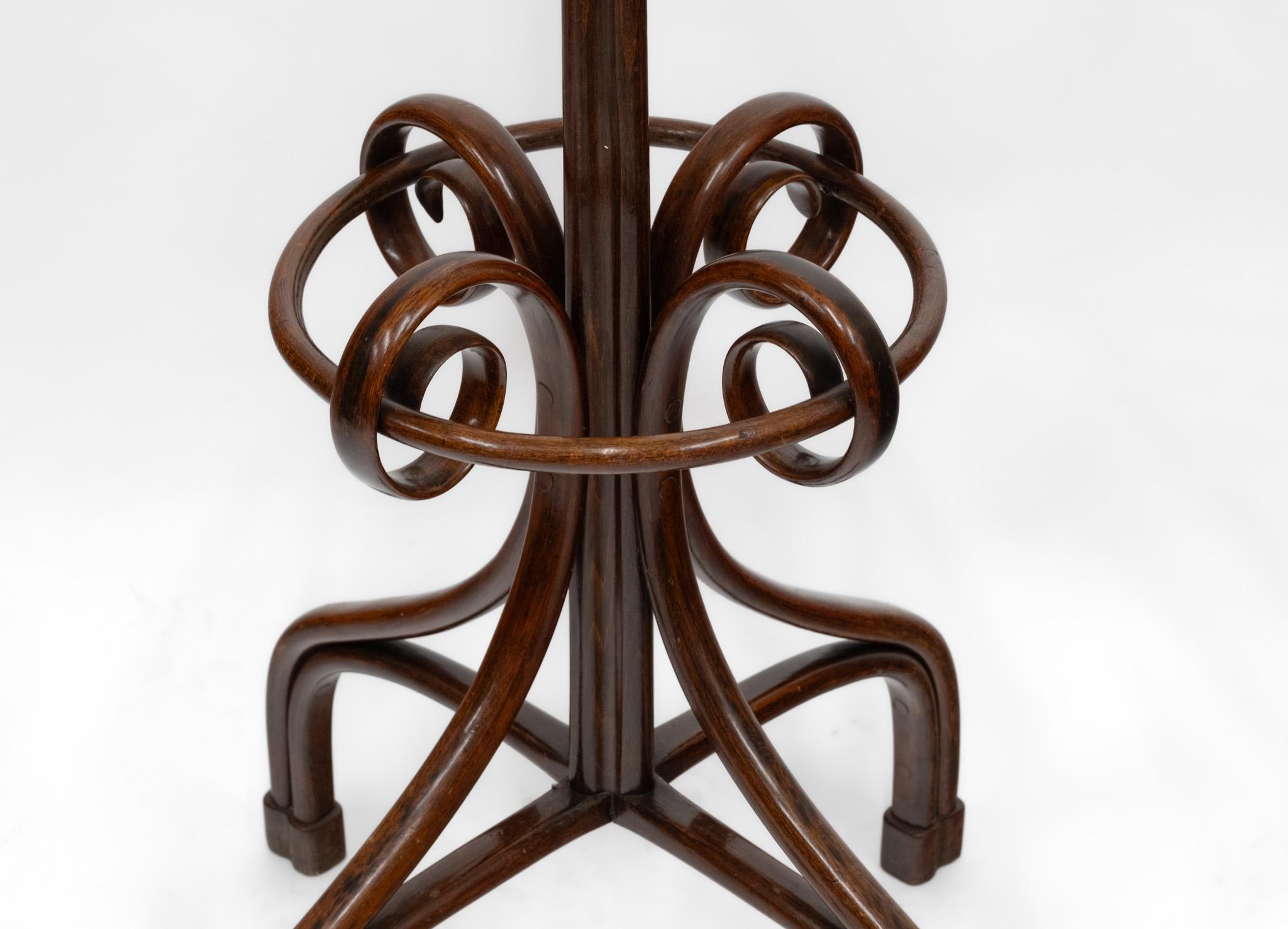 Un bon porte-manteau en bois courbé du début du 20e siècle. Circa 1900.

Les pieds reposent sur quatre grandes jambes inclinées vers le bas, chacune avec une volute entourant un rayon de cercle pour tenir des bâtons et des parapluies. Le