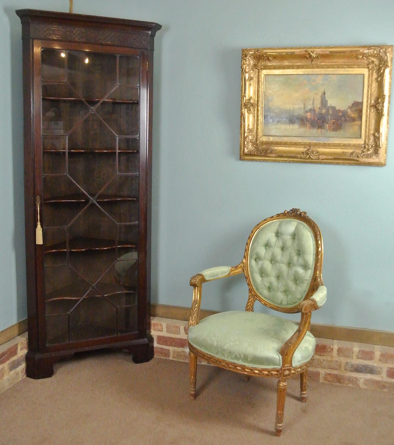 A very beautiful Georgian corner display cabinet with single astagral glazed door with original hinges, escutcheon and a working (later but well fitted) lock and key.  The blind fretwork carved frieze of Chinese Chippendale design beneath an ogee