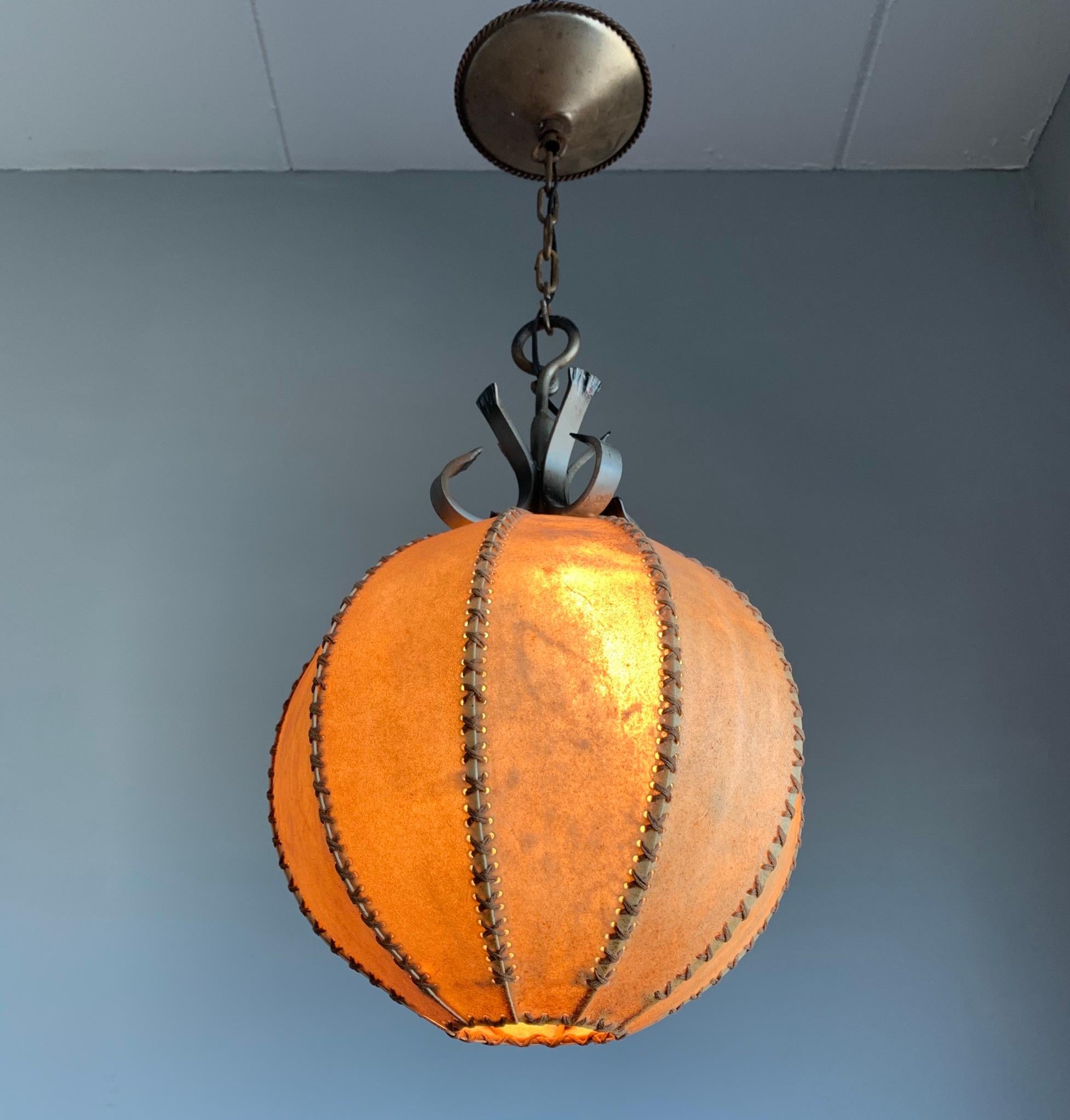 Beautiful shape and excellent condition antique pendant. 

This early 1930s leather pendant comes with a wrought iron chain and ceiling cap. The shape, the color and the effect of the light shining through the natural hide make this pendant a real