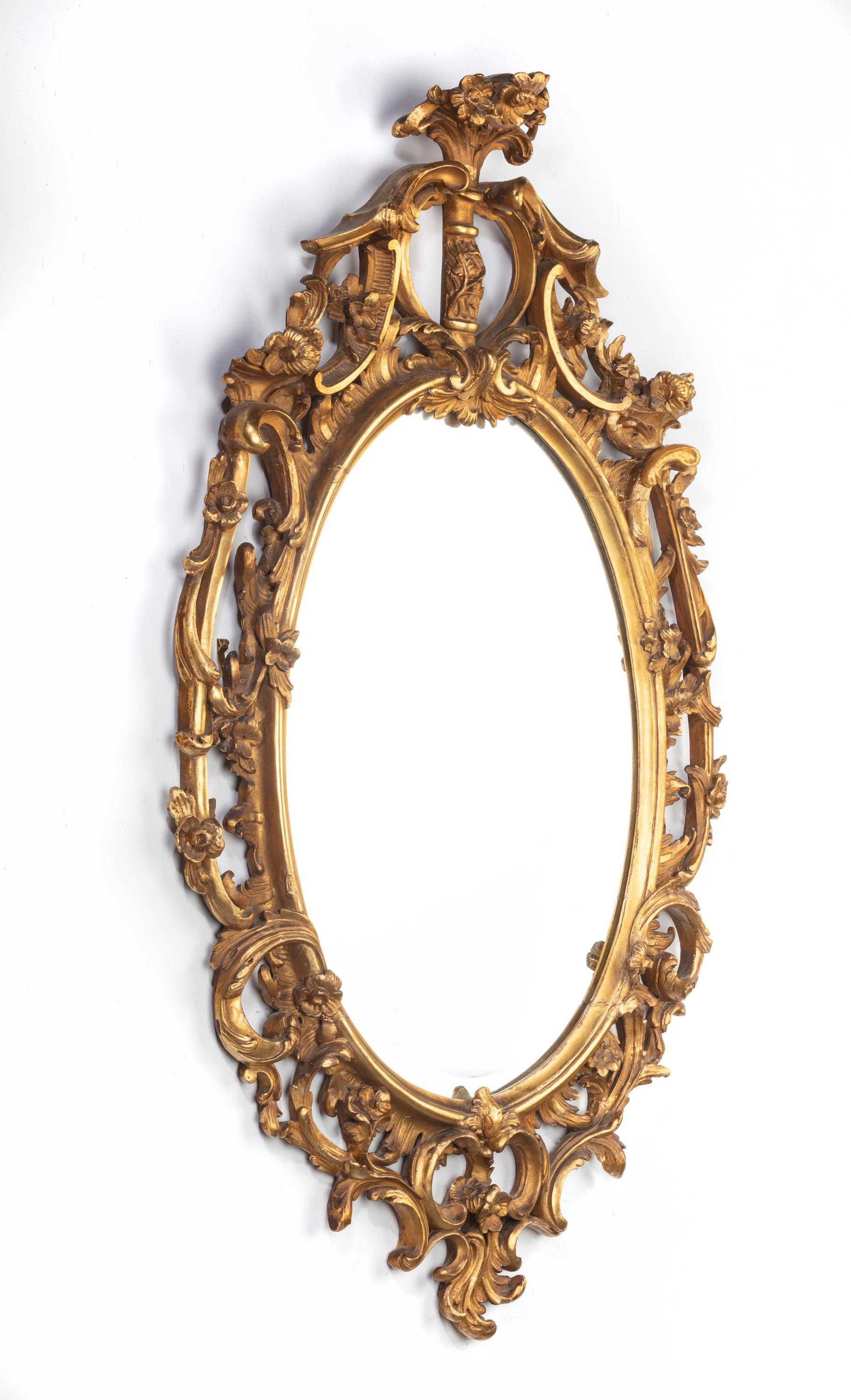 A good pair of George III period oval, giltwood mirrors. The gilding was probably restored in the 19th century with an oil finish. With attractively carved scrolled details and an abundance of foliage, flowers and leaves.
 