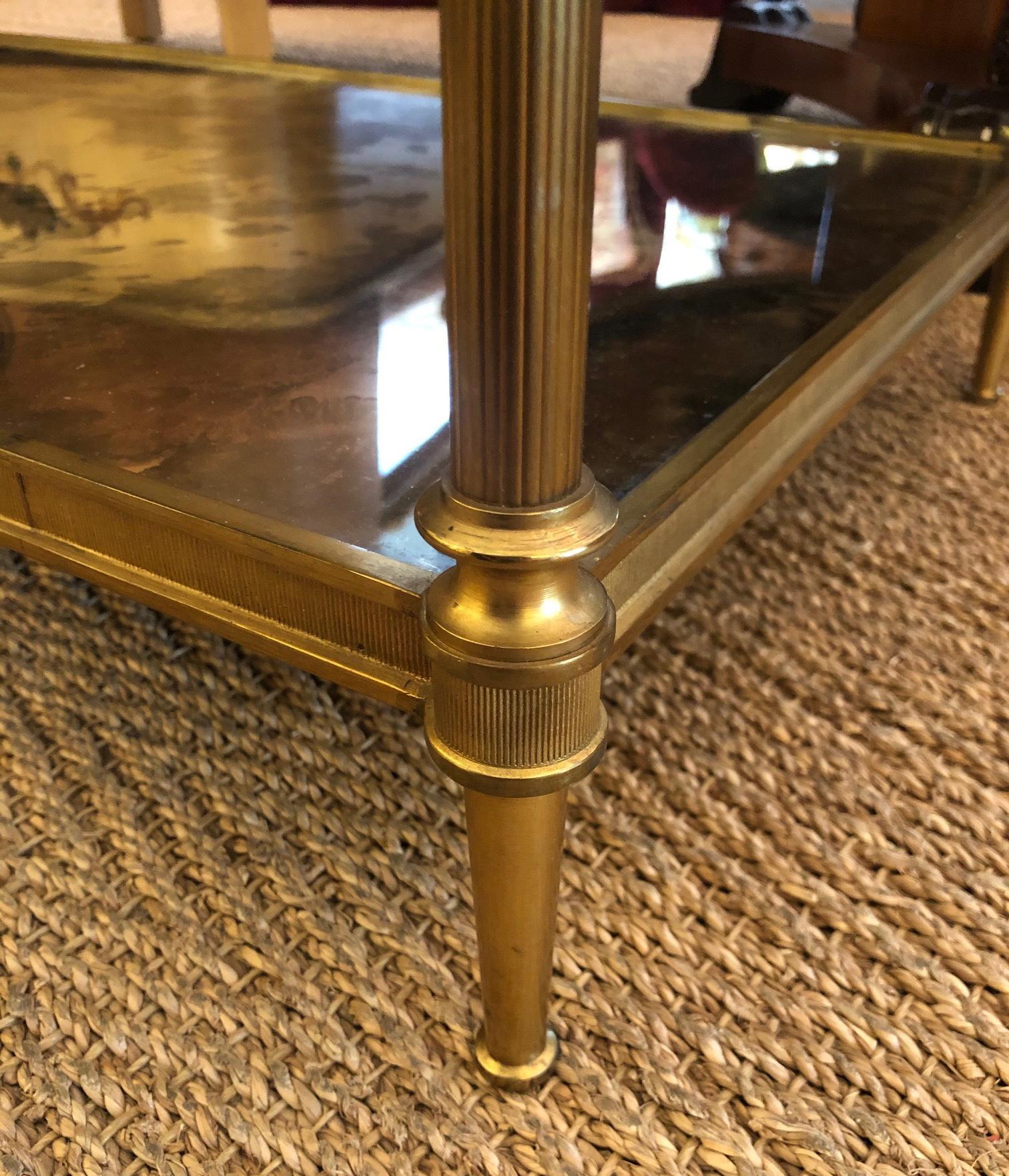 Of solid gilt-bronze in the timeless neoclassical style favored by Louis XVI of France and revitalized by Maison Jansen in the 20th century; the inset oxidized mirrored top with reeded apron and raised on reeded supports joining a similar lower