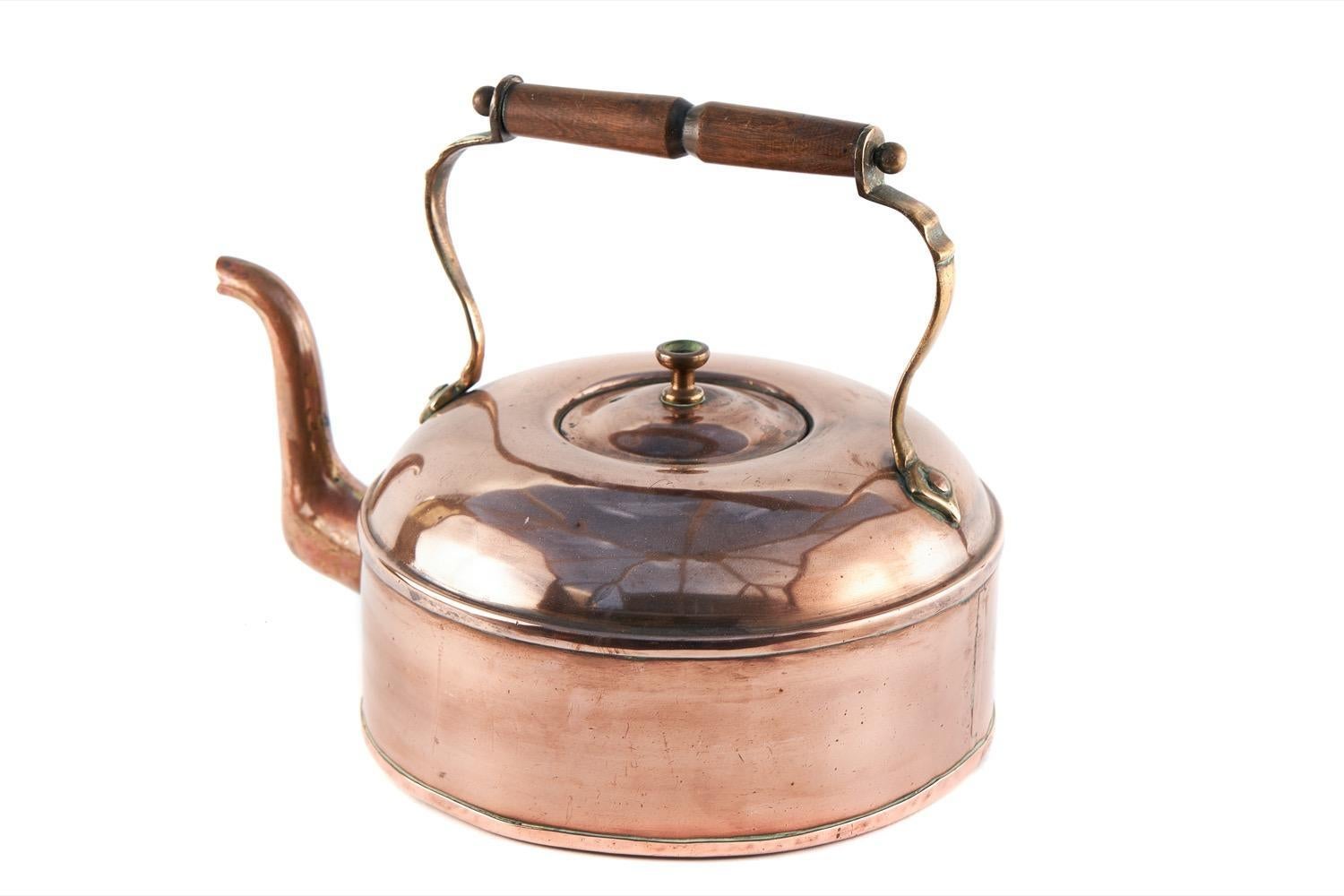 Il s'agit d'une bouilloire ancienne en cuivre de bonne qualité du 19e siècle, de forme trapue, avec une poignée rotative en bois, un couvercle amovible et un bec verseur de forme classique.