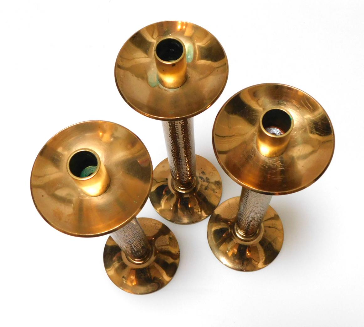 Each heavy candlestick with hand-hammered shaft below a circular cup; all resting in a circular splayed base.