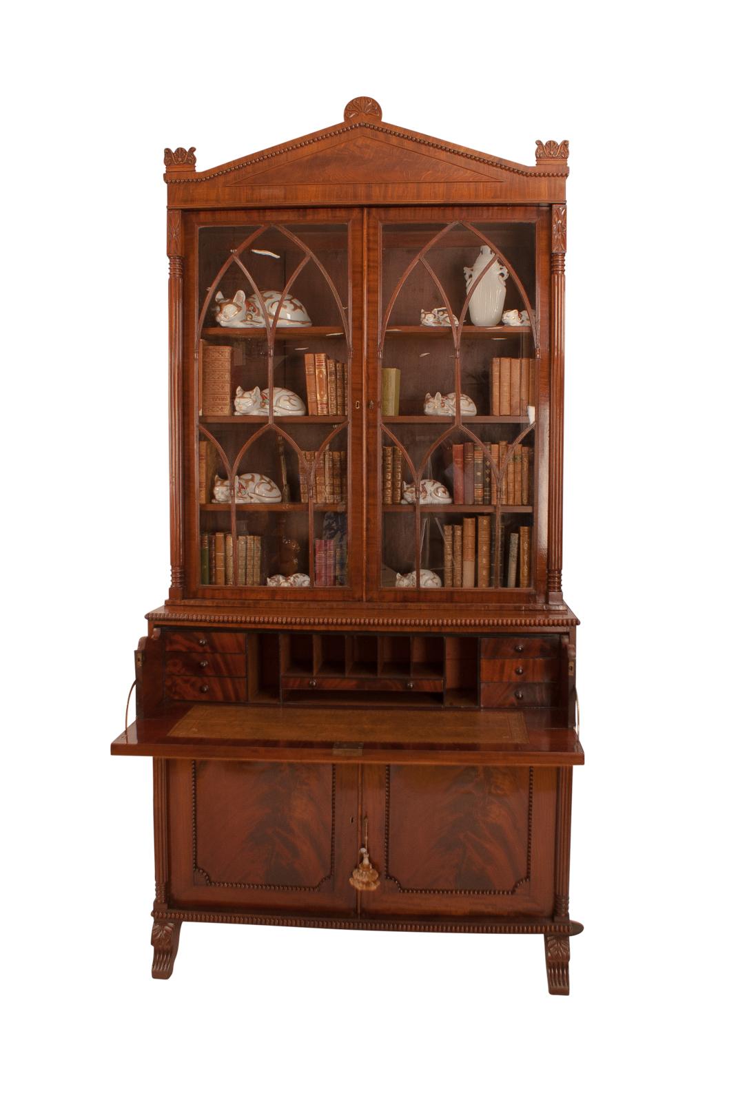 An English Regency Period mahogany cabinet bookcase with a secretary drawer and Gothic glazing, circa 1820. This piece has unusually nice wood with sophisticated classical design. The cabinet features a pediment with inlay, Gothic glazing and well