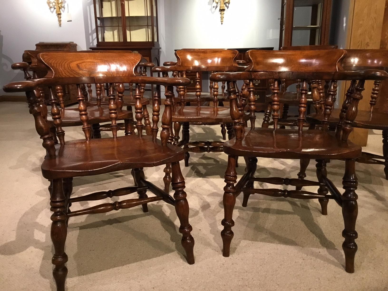 A good set of eight ash and elm Victorian period captains chairs. Each having a bowed back support with shaped open arms and turned spindle supports. Having beautifully figured ash dished 