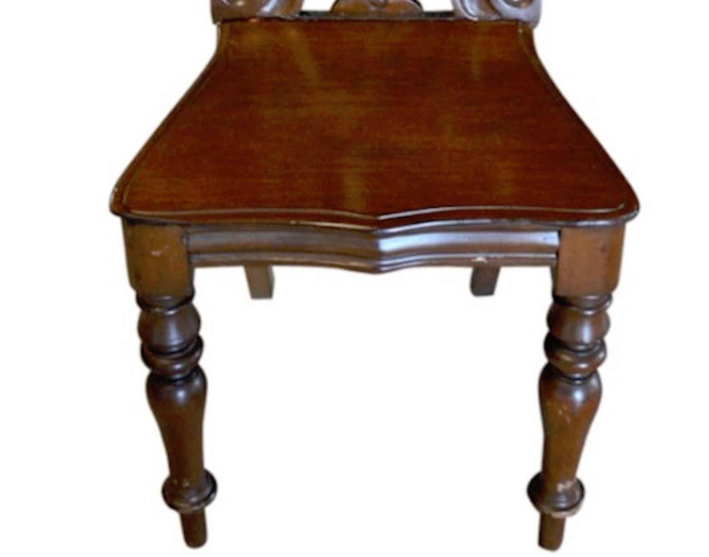 A good single English mahogany hall chair of solid walnut with finely detailed scroll work.