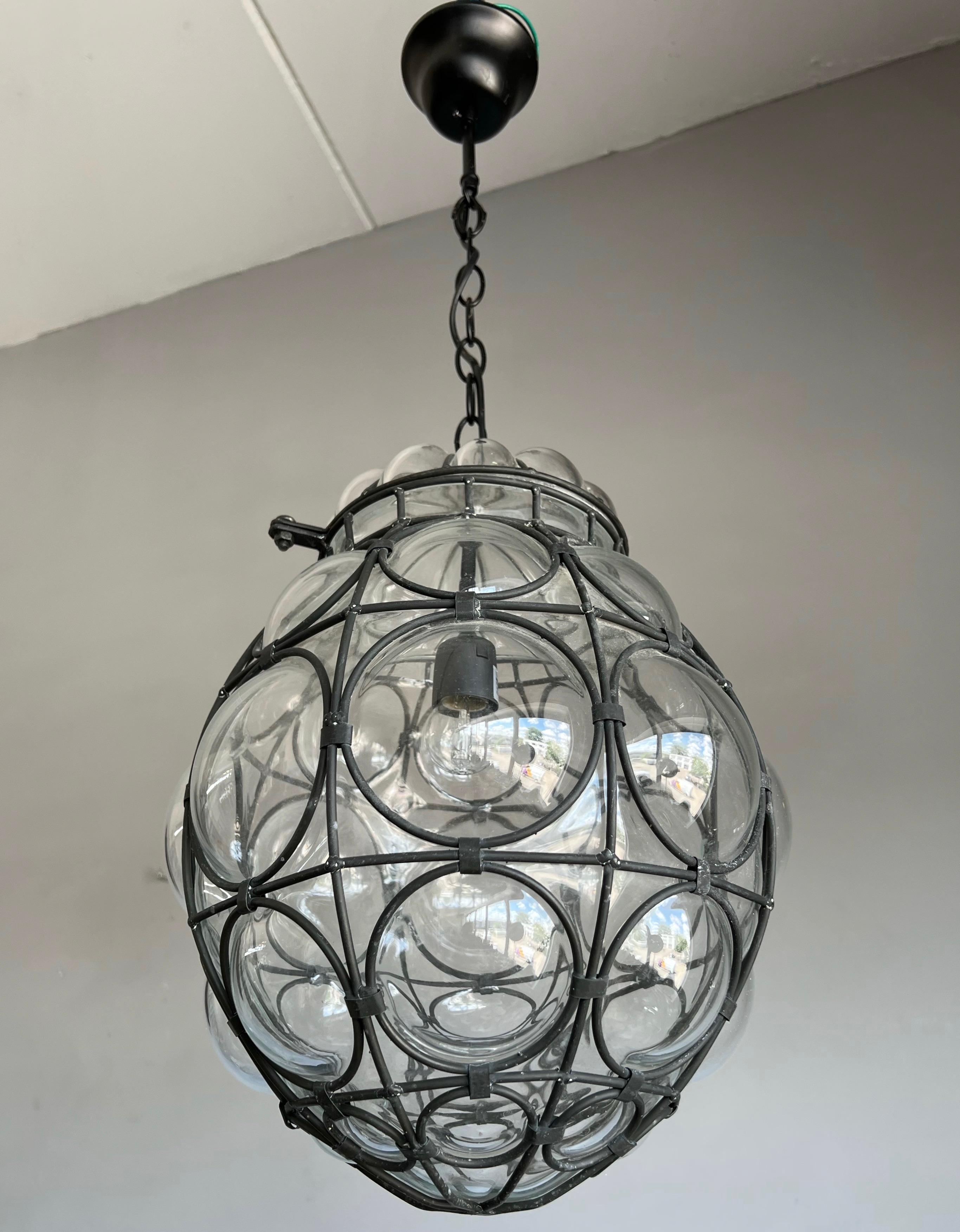 Good size, mid century made and great condition light fixture. 

This stylish Venetian pendant is in excellent condition and the transparent glass is perfectly and symmetrically blown into the geometrically circular metal frame and the result is