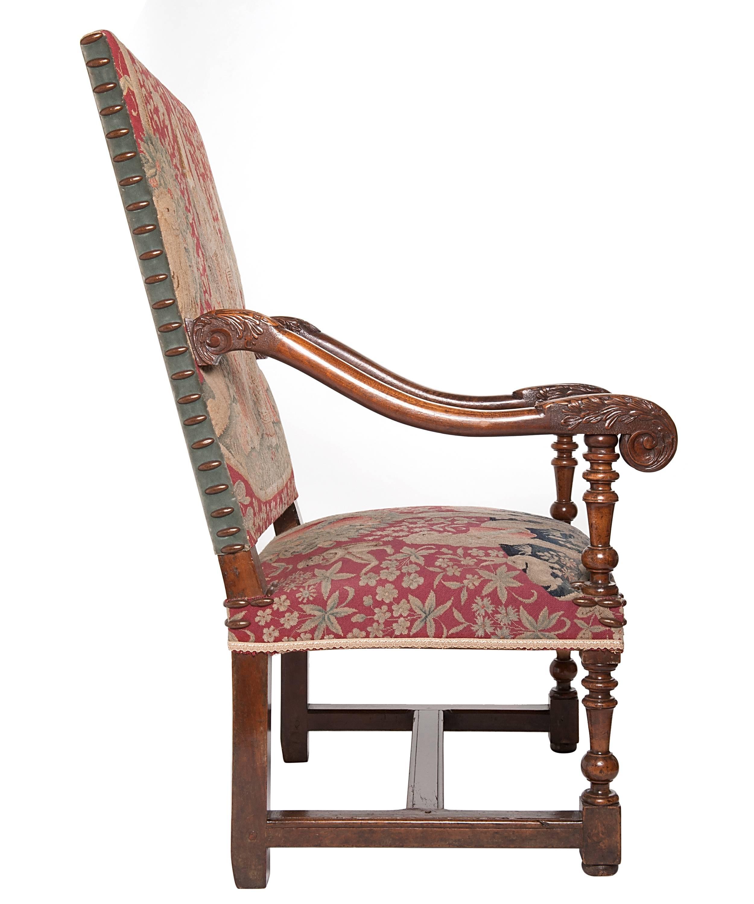 A very good large walnut armchair with slightly slanted rectangular backrest and padded seat. With floral carved scrolled arms finishing in 'bec de corbin'. On block and spooled turned legs linked by a 'H' shaped stretcher. The chair upholstered in