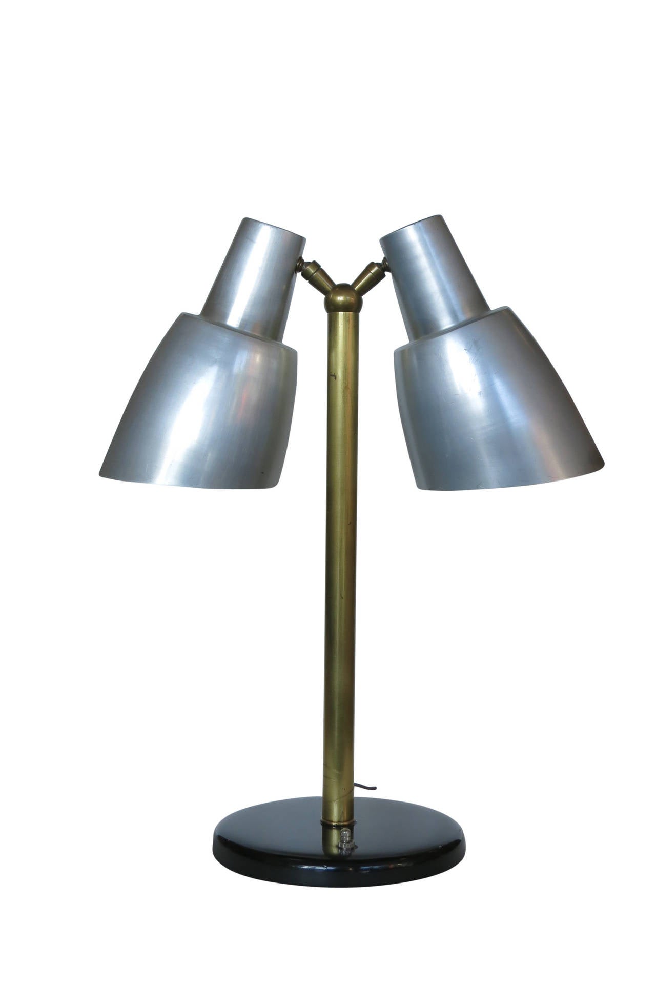 This piece is a midcentury Googie double table lamp with aluminum lamp shades, brass stem, and black lacquered base. This piece was used as a prop in filming the inside of the Ford offices in Disney's 2019 movie 