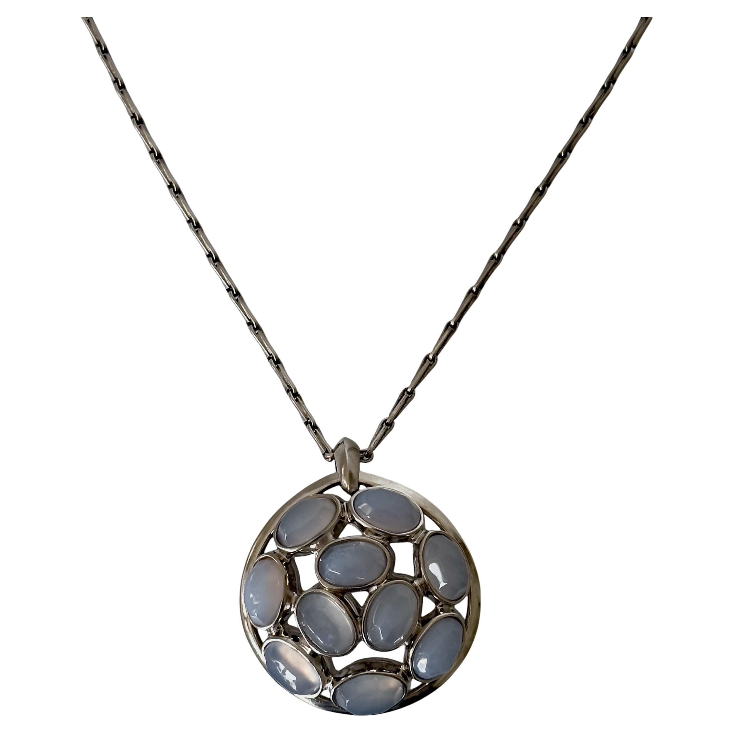 Scopri la sottile armonia di questa collana con medaglione di calcedonio blu a doppia faccia con finitura in palladio, un pezzo eccezionale che combina un'eleganza senza tempo con un design contemporaneo. Ornata da pietre di calcedonio in tonalità