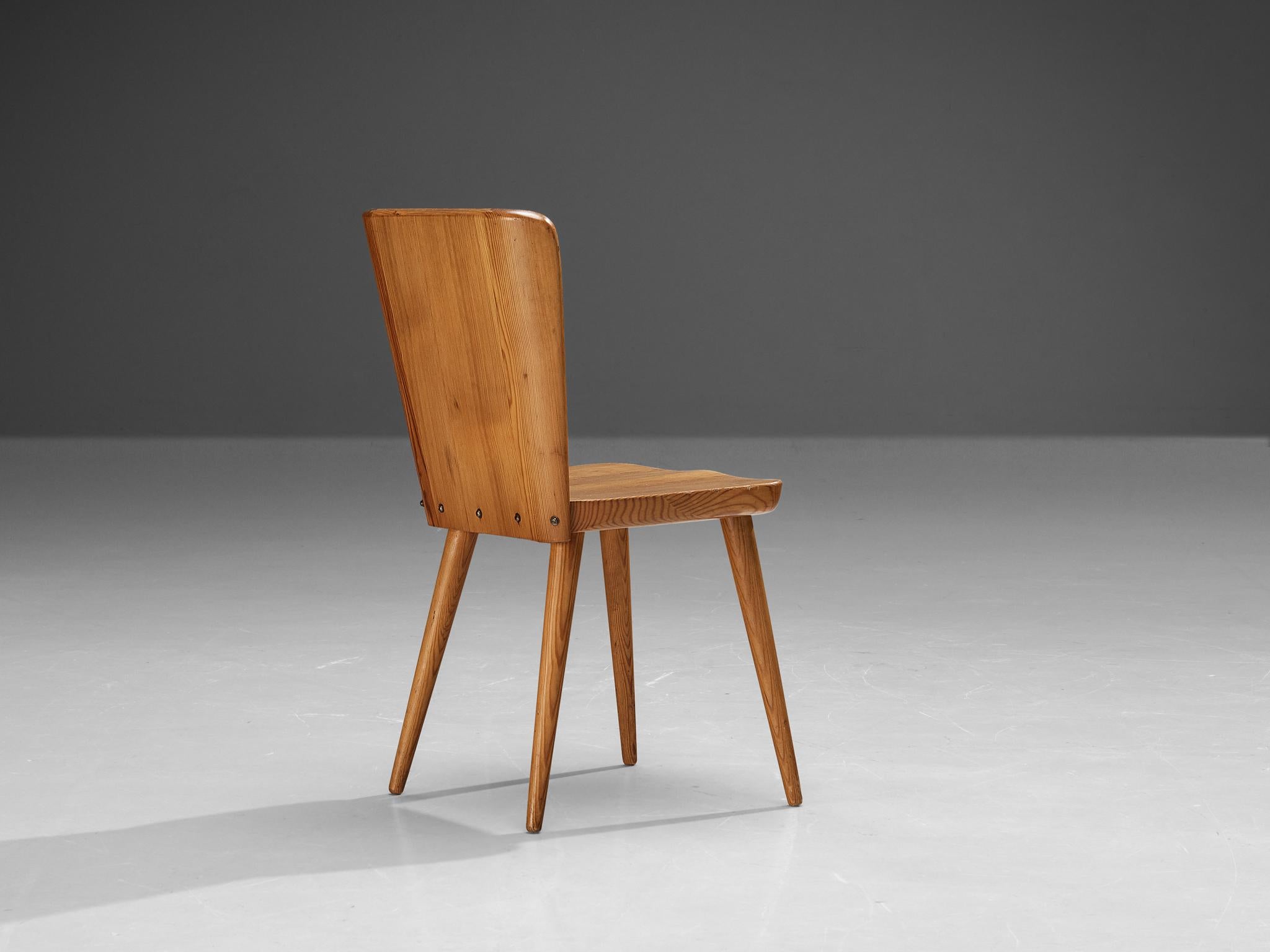 Göran Malmvall for Svensk Fur, dining chair, pine, Sweden, 1940s. 

This Swedish dining chair holds a strong expression with this sturdy shaped design. The backrests runs wide near the top and consists of straight and slightly curved near near the