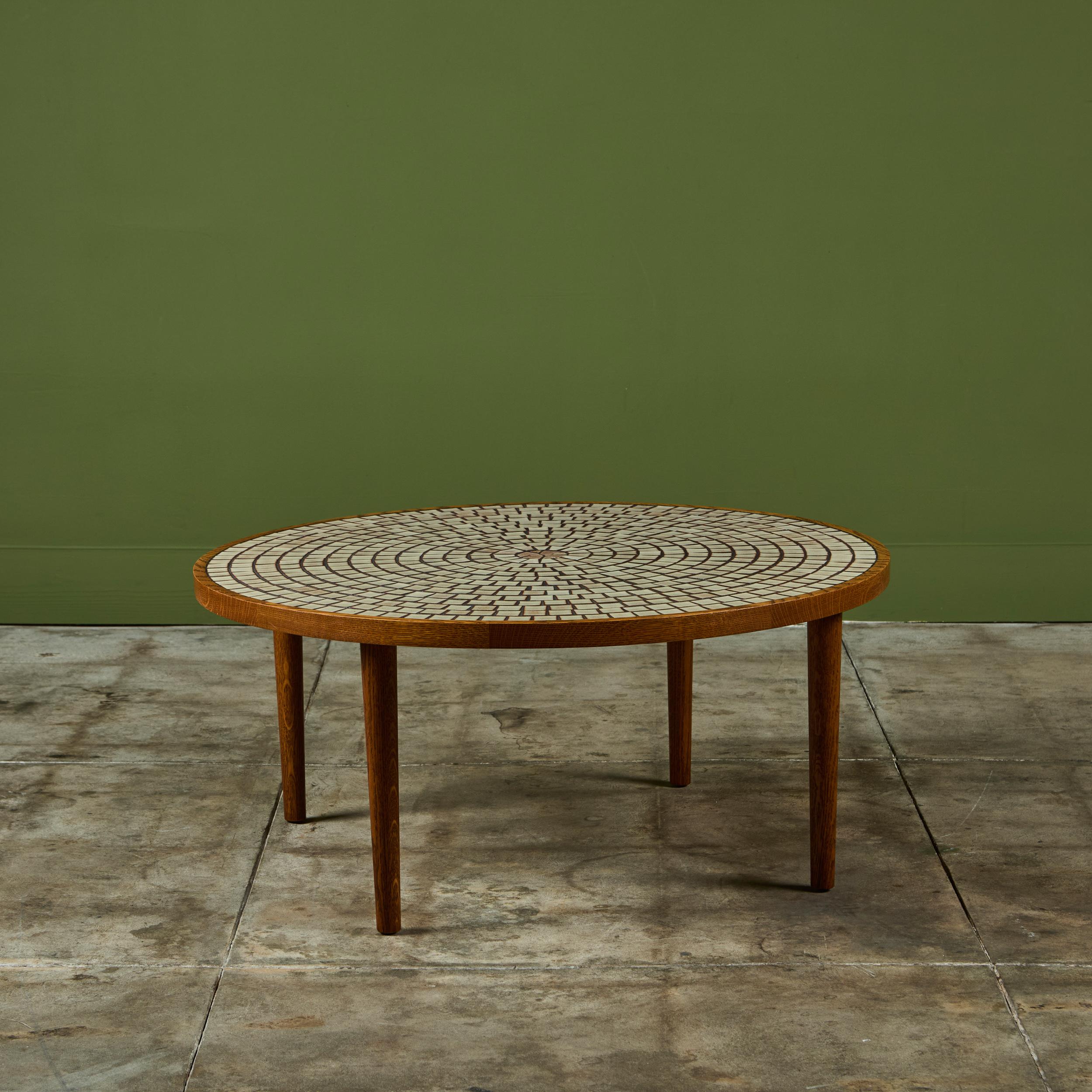 Tavolino rotondo di Gordon & Jane Martz per Marshall Studios, anni '60 circa, USA. Il piano del tavolo è intarsiato con piastrelle quadrate e triangolari in ceramica smaltata di tonalità avena in un motivo geometrico. La struttura e le quattro gambe