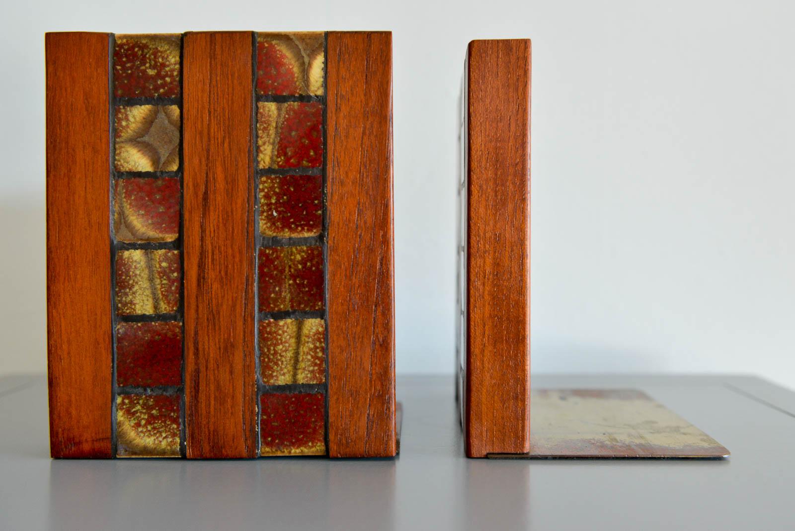 Gordon and Jane Martz Walnut and ceramic tile inlay bookends, circa 1960. Walnut cubes with brass detail and red/gold ceramic tile inlay. Brass has some patina to base, however is unseen when used as intended. Very good condition