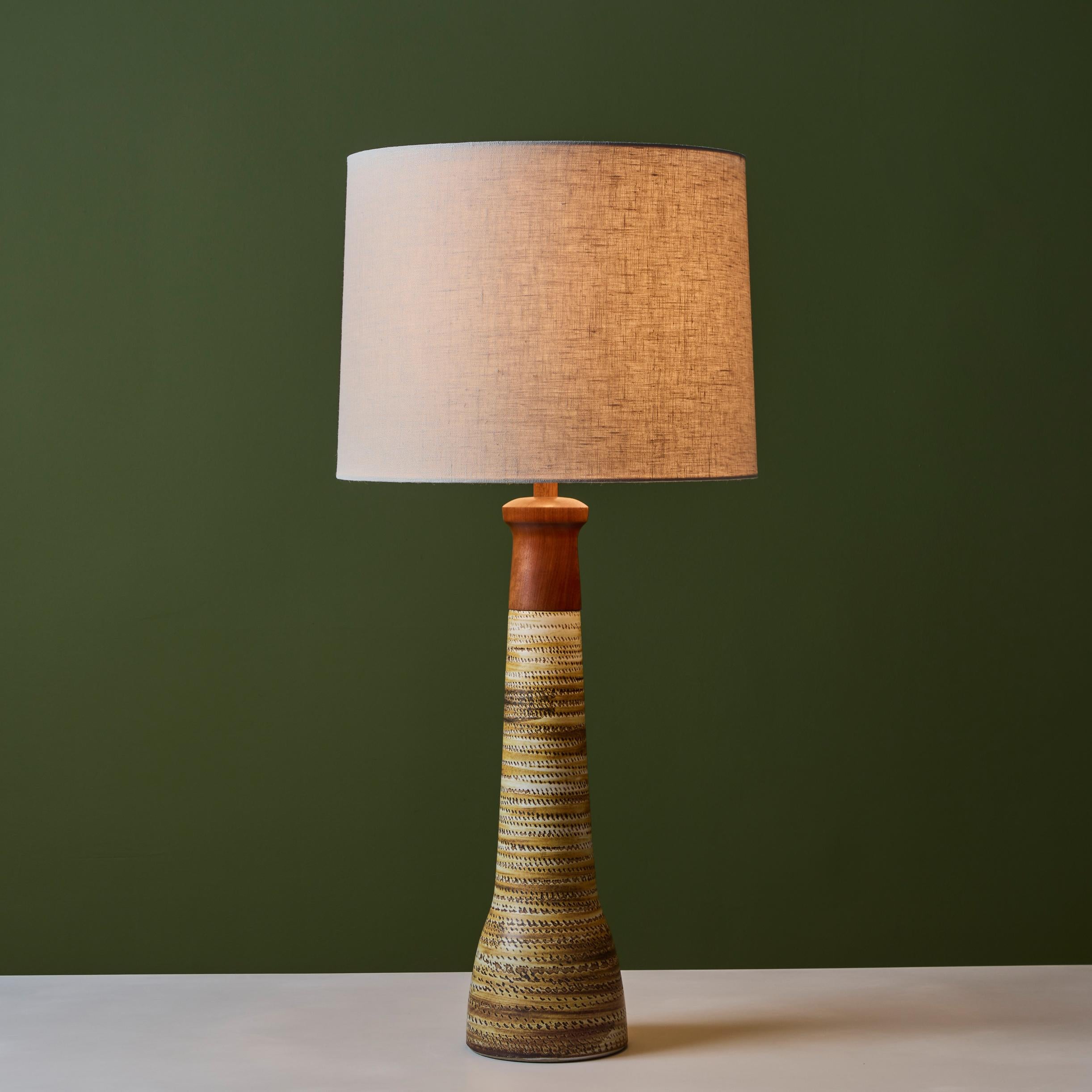 Ceramic and walnut table lamp from Midwestern ceramic artists Gordon and Jane Martz for their company Marshall Studios. The table lamp has a ceramic cylindrical stem capped with walnut top. The lamp has a new linen shade and has been newly
