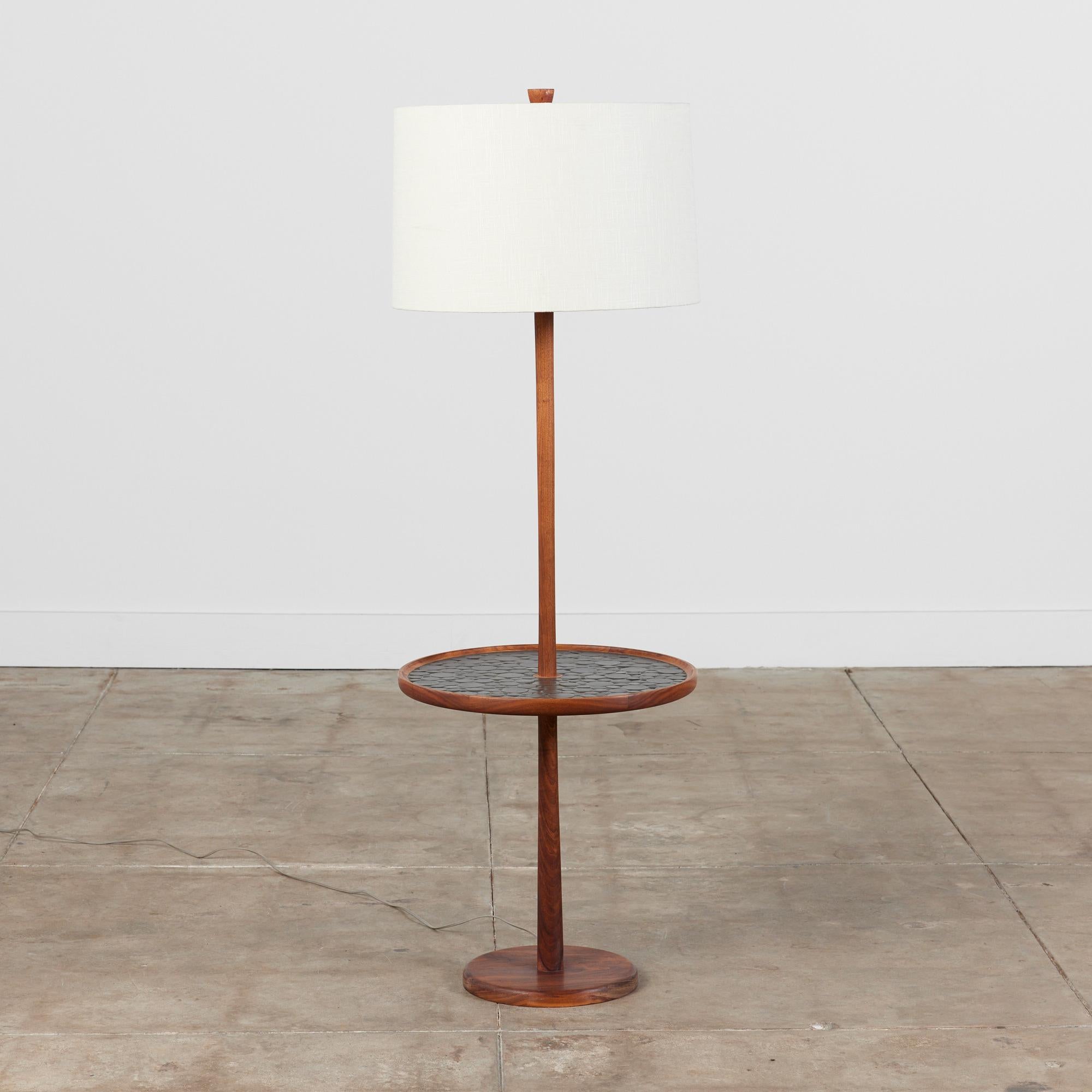 Gordon & Jane Martz floor lamp with mosaic tile round side table. This piece features a walnut base with inlaid black ceramic coin tiles on the table top. The lamp has a newly made linen shade and original wiring.

Dimensions:
18.25
