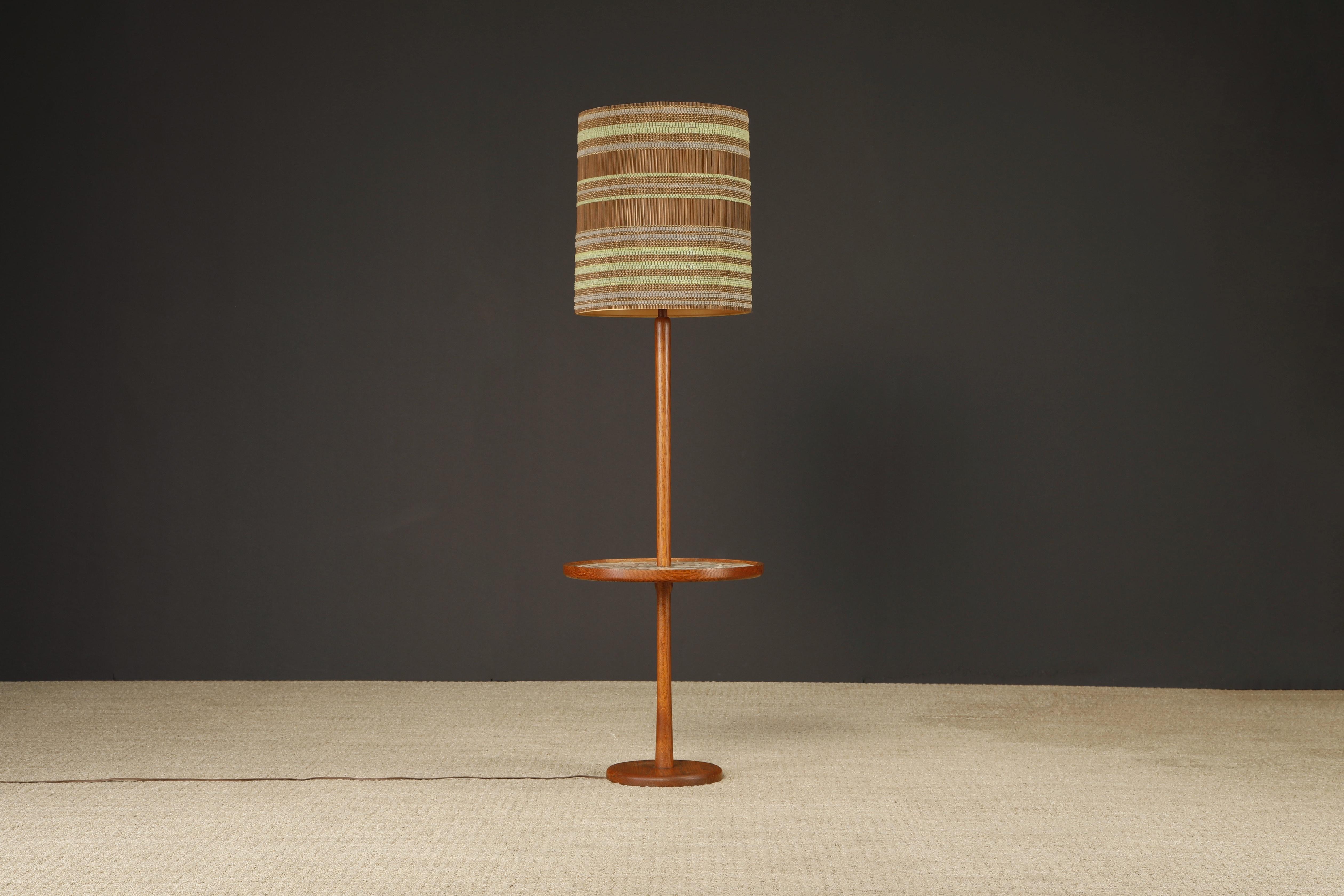 Esta elegante lámpara de pie de roble teñido de los años 60 con mesa auxiliar incorporada, obra de Gordon & Jane Martz para Marshall Studios, está en un increíble estado original de época, con una hermosa pátina clara. La mesa auxiliar redonda