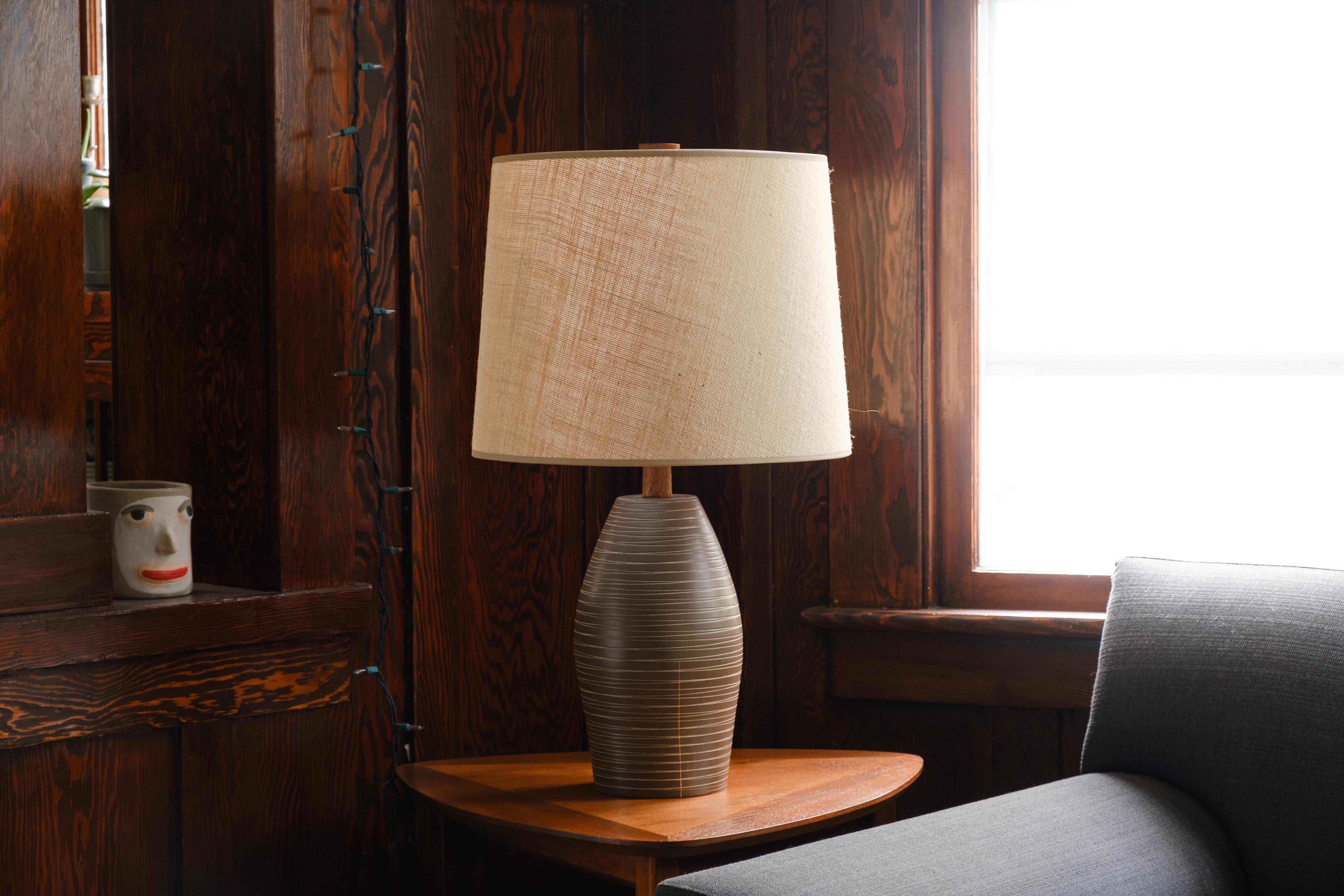 💡 What is it?
—
These signed Martz model #267 lamp come in a matte dark brown glaze and yes, this lamp has been broken and repaired with gold kintsugi. The lamp features an incised, horizontal pattern that runs top to bottom, surrounding the entire