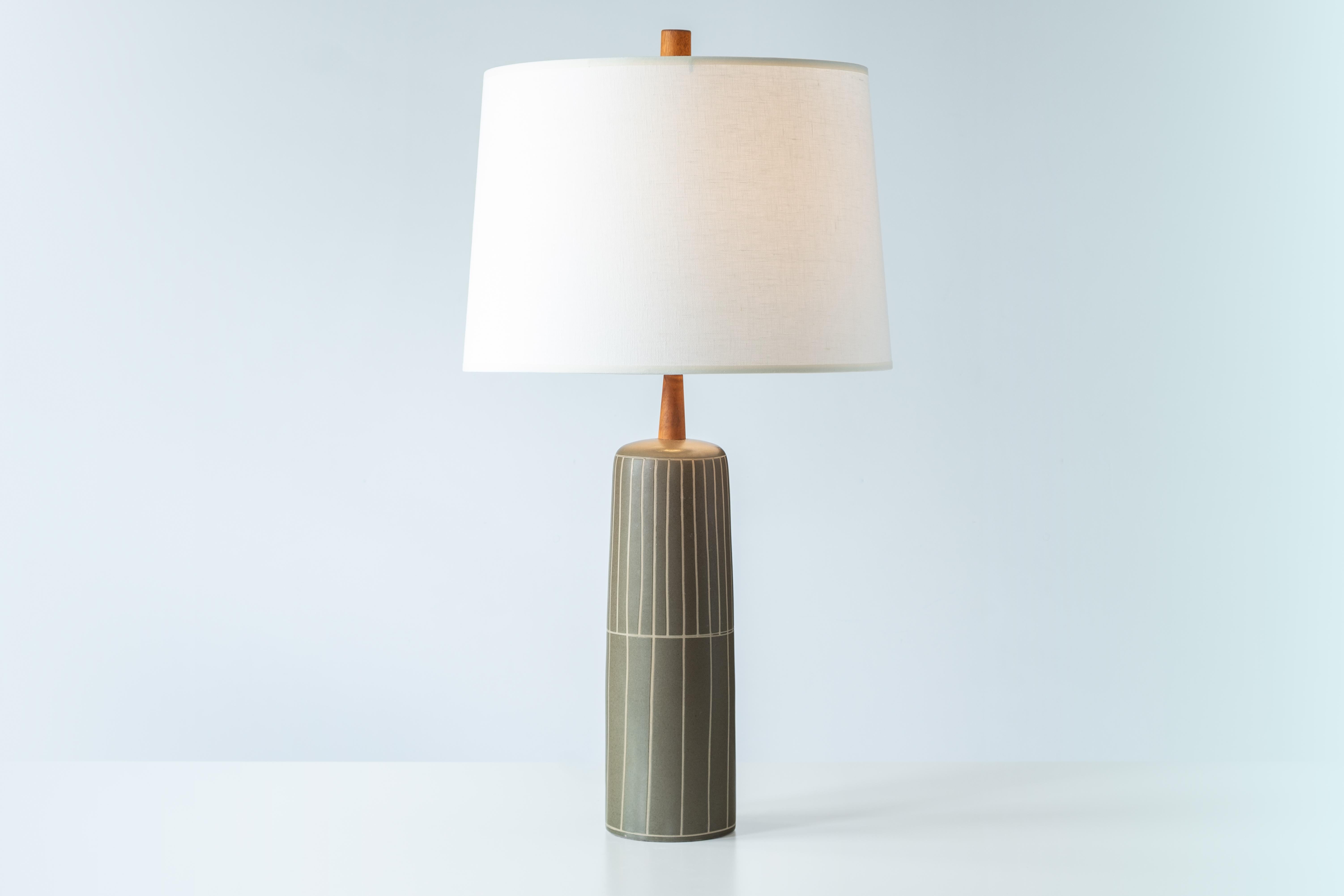 WHAT IS IT?
—
This Martz lamp is glazed in a dark olive green glaze, and decorated with an incised vertical line design that runs from top to bottom around the lamps. The line pattern is tighter on top, and looser on the bottom. Truly a simple,
