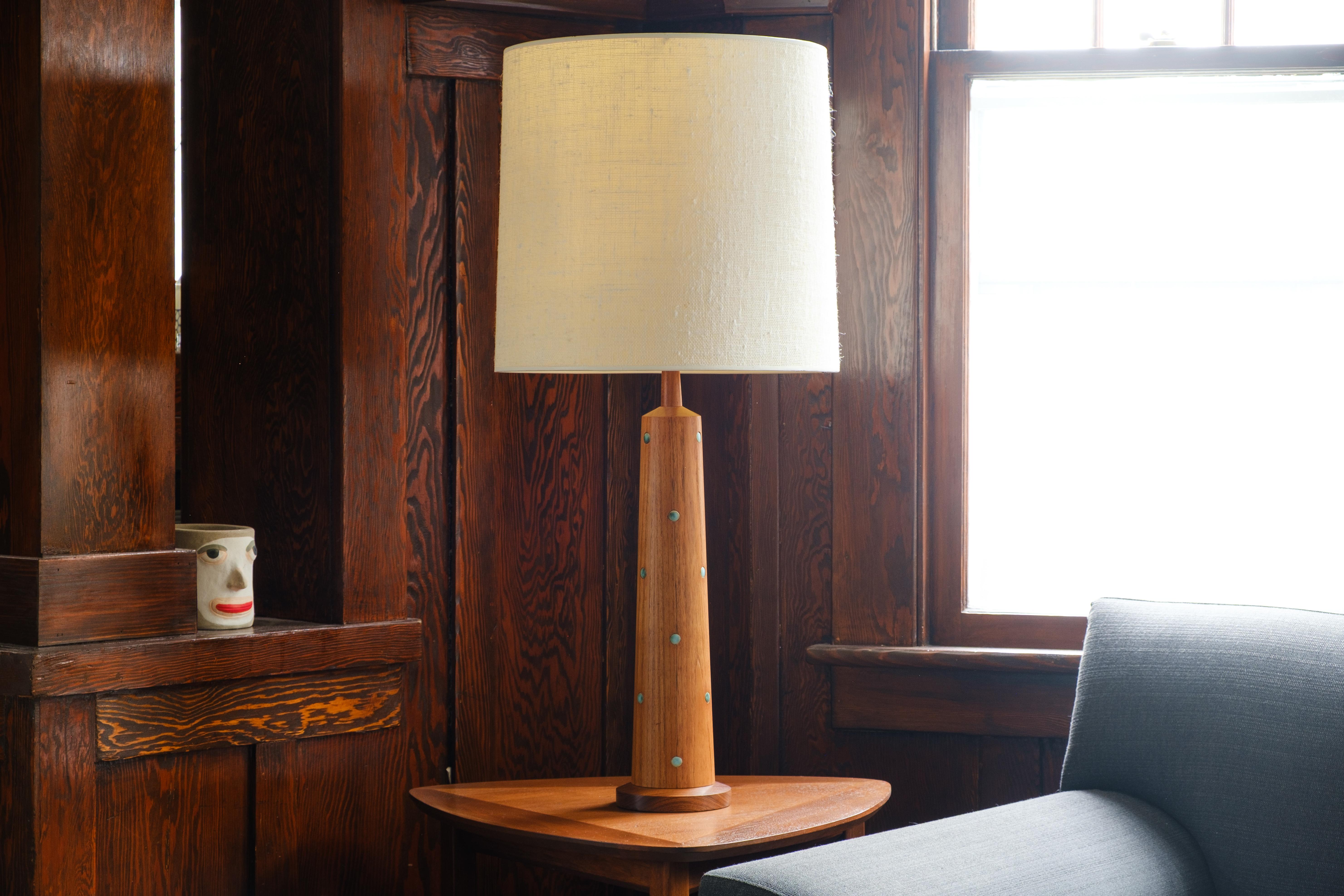 💡 What is it?
—
Another gem from the masters of mid century lightning – Gordon and Jane Martz. This substantial Martz model WL2-28 lamp is comprised of a 3-part tapered teak wood base and is inlayed with a repeating pattern of small circular tiles.