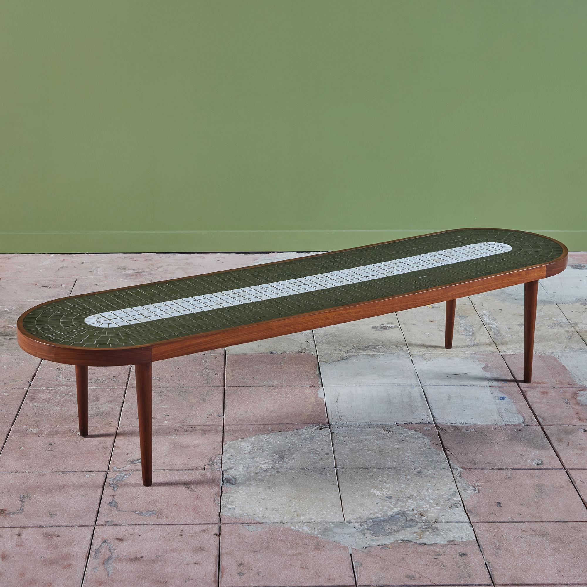 Long oval coffee table by Gordon & Jane Martz for Marshall Studios. The table top is inlaid with black and white square ceramic tiles. The frame of the table and four legs are solid walnut.

Dimensions
72.75