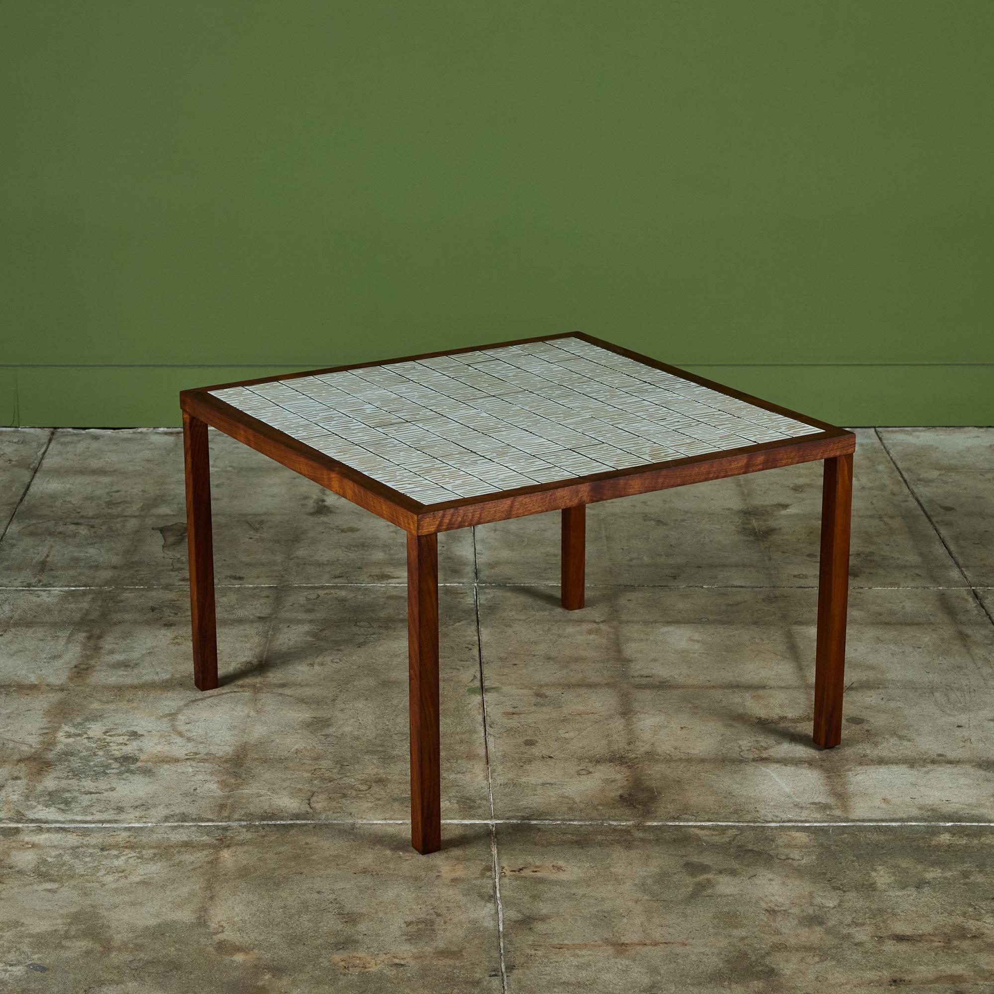 Square side table by Gordon & Jane Martz. The table top is inlaid with square ceramic tiles in a cream glaze with incised linear detailing exposing the stoneware beneath. The frame of the table and four legs are solid walnut.
 
Dimensions
30.25