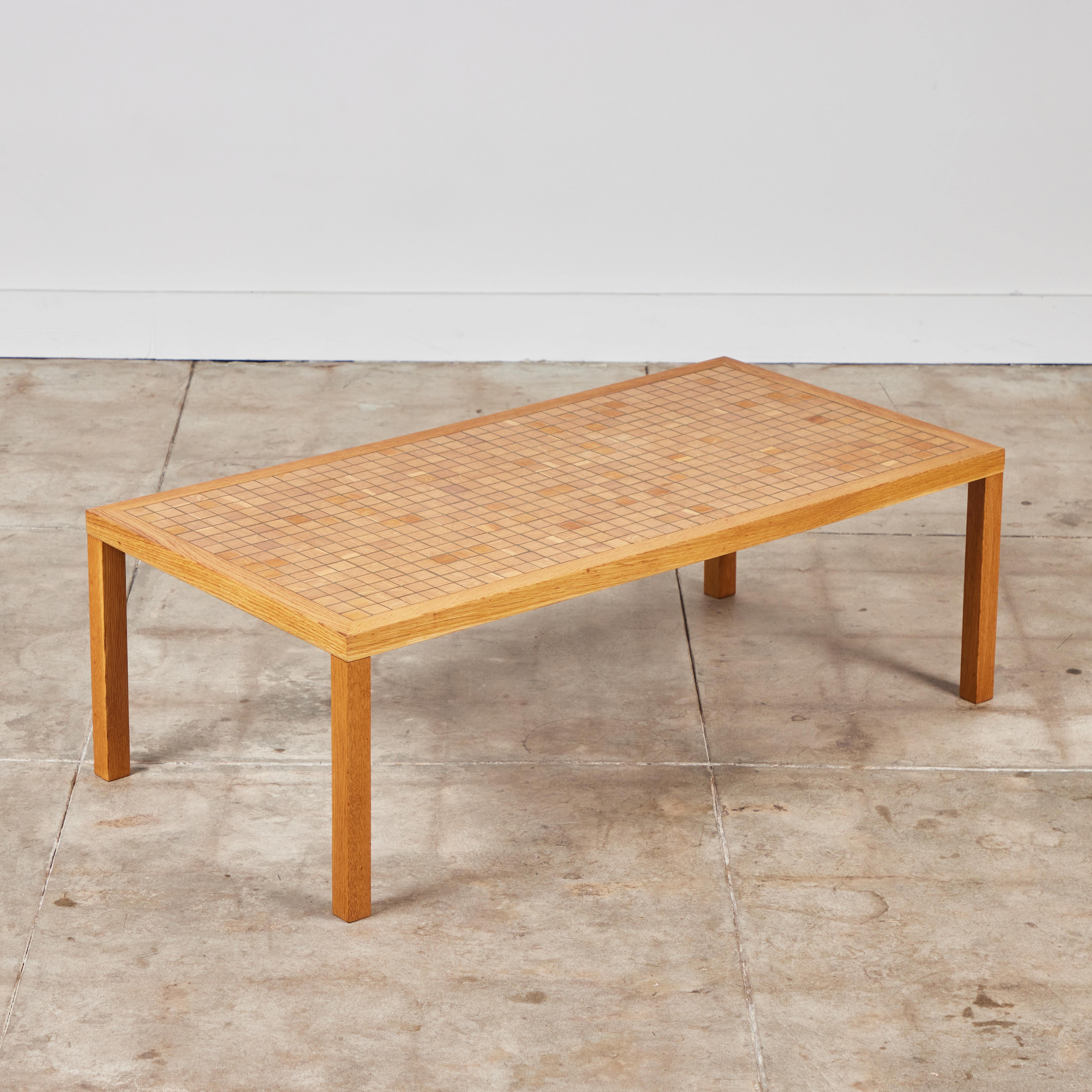 Rectangular oak coffee table by Gordon & Jane Martz for Marshall Studios, c.1960s, USA. The table top is inlaid with square oak tiles in a linear pattern. The tiles feature varying wood grains and brown tones . The frame and legs of the table are