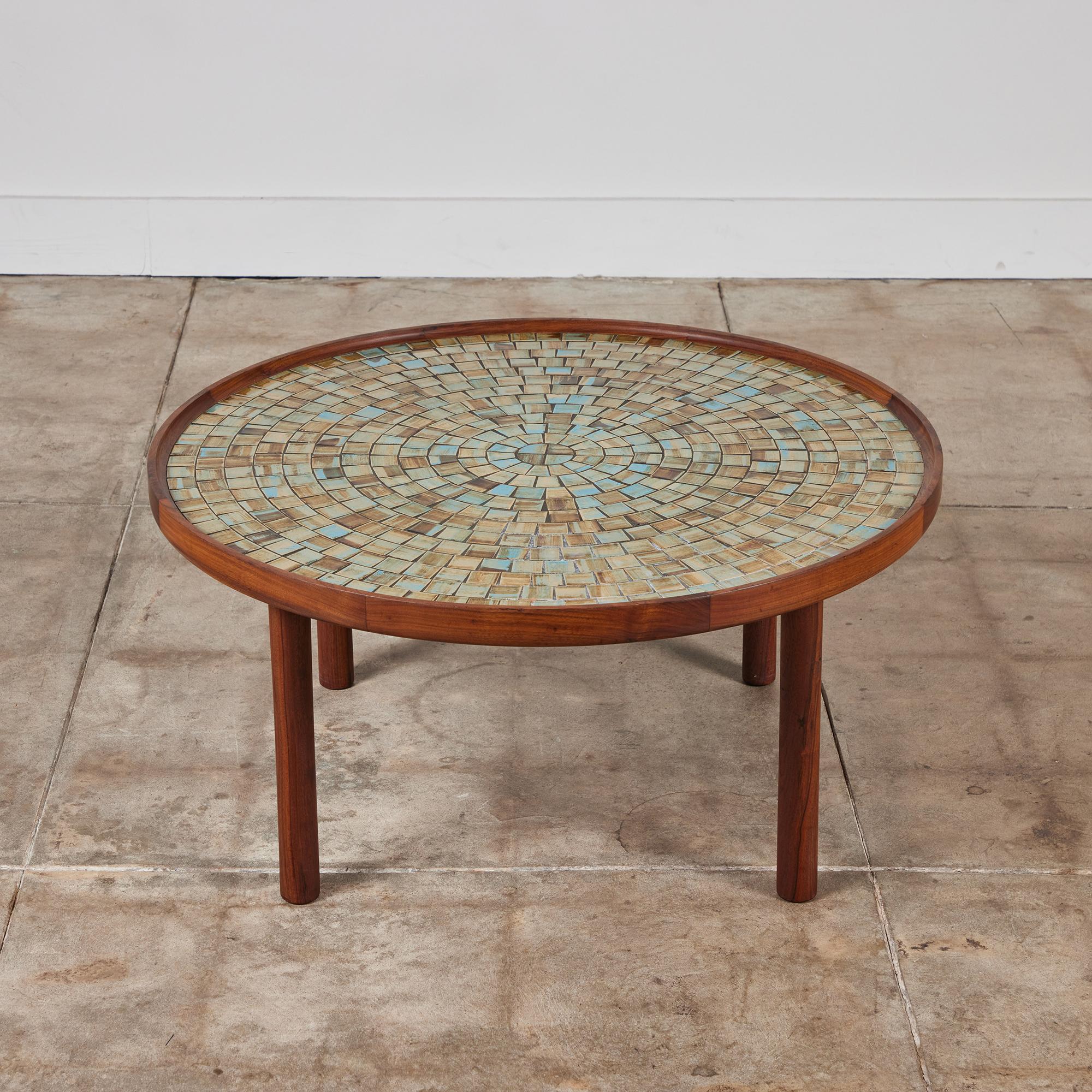 Round coffee table by Gordon & Jane Martz for Marshall Studios c.1960s, USA. The table top is inlaid with square and triangular blue, brown and beige glazed ceramic tiles in a geometric pattern. The frame and four rounded legs of the table are all