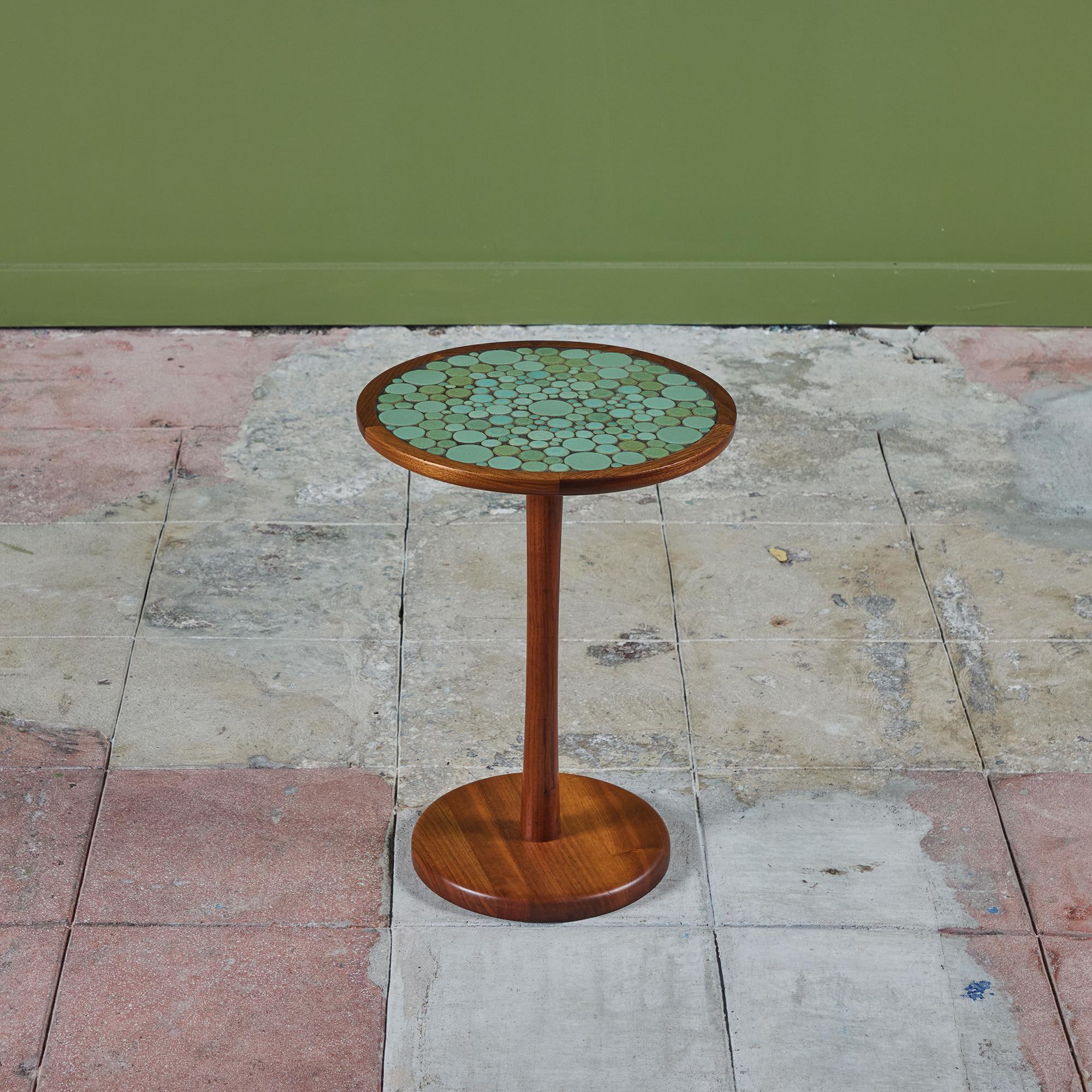 Round side table by Gordon & Jane Martz. The table top is inlaid with ceramic coin tiles in a sea foam green matte glaze. The frame, base and pedestal of the table are all solid walnut.

Dimensions
14