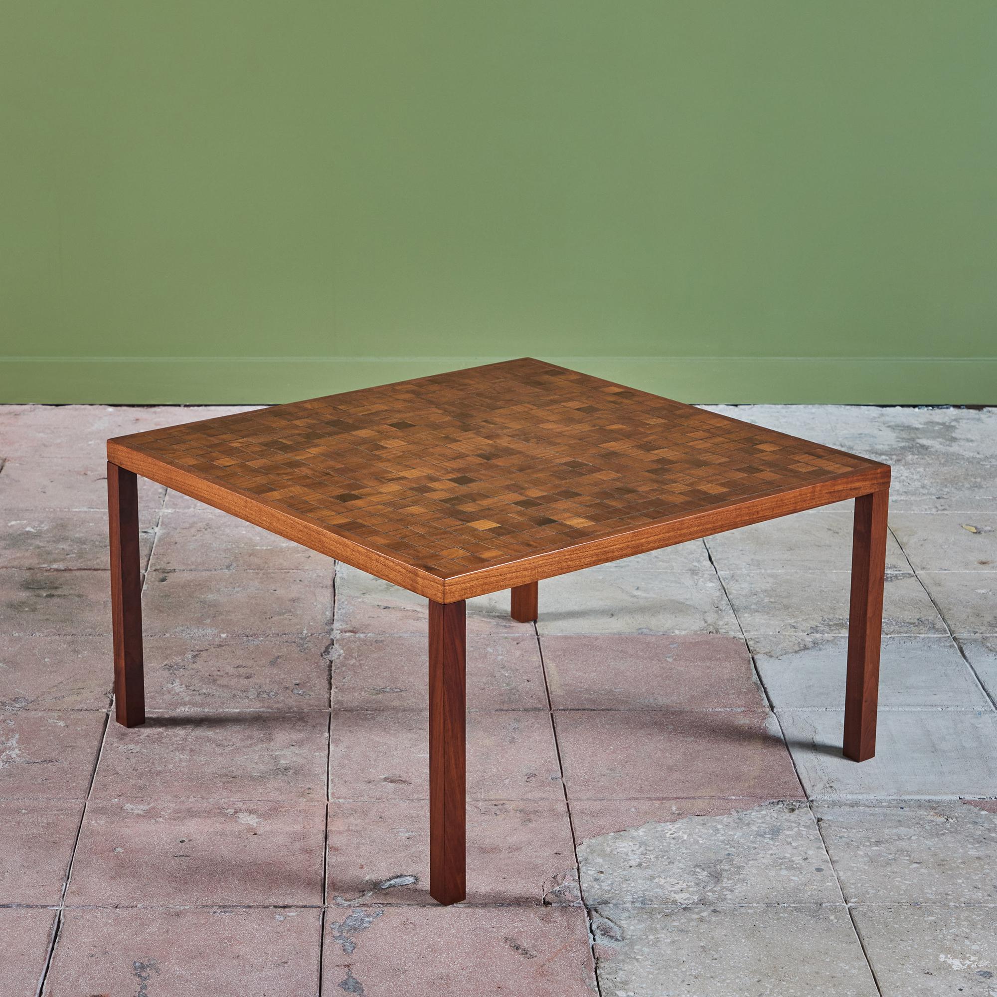 Square walnut coffee table by Gordon & Jane Martz. The table top is inlaid with square tiles in a geometric pattern. The tiles feature varying wood grains and brown tones. The frame, and table legs are solid walnut.

Dimensions
﻿29