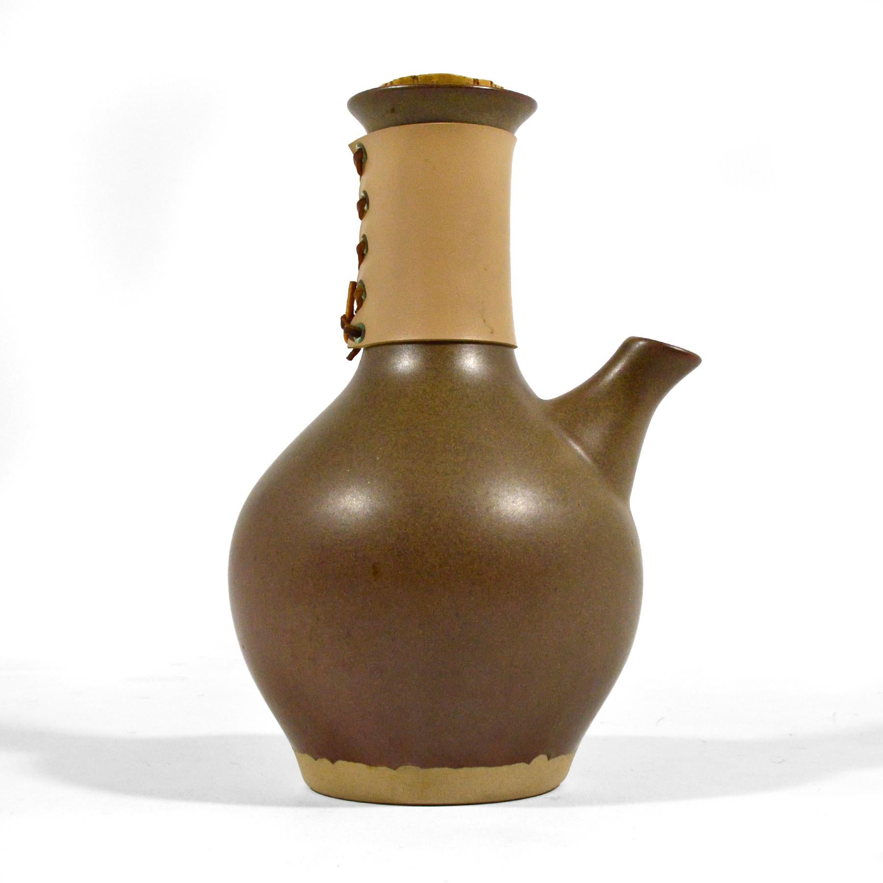 Beautiful in form and highly functional, this model M132 carafe/ coffee server by Gordon & Jane Martz for Marshall Studios has a great organic shape, is glazed in their signature subtle rabbit's fur glaze, and has a leather-wrapped handle. Perfectly