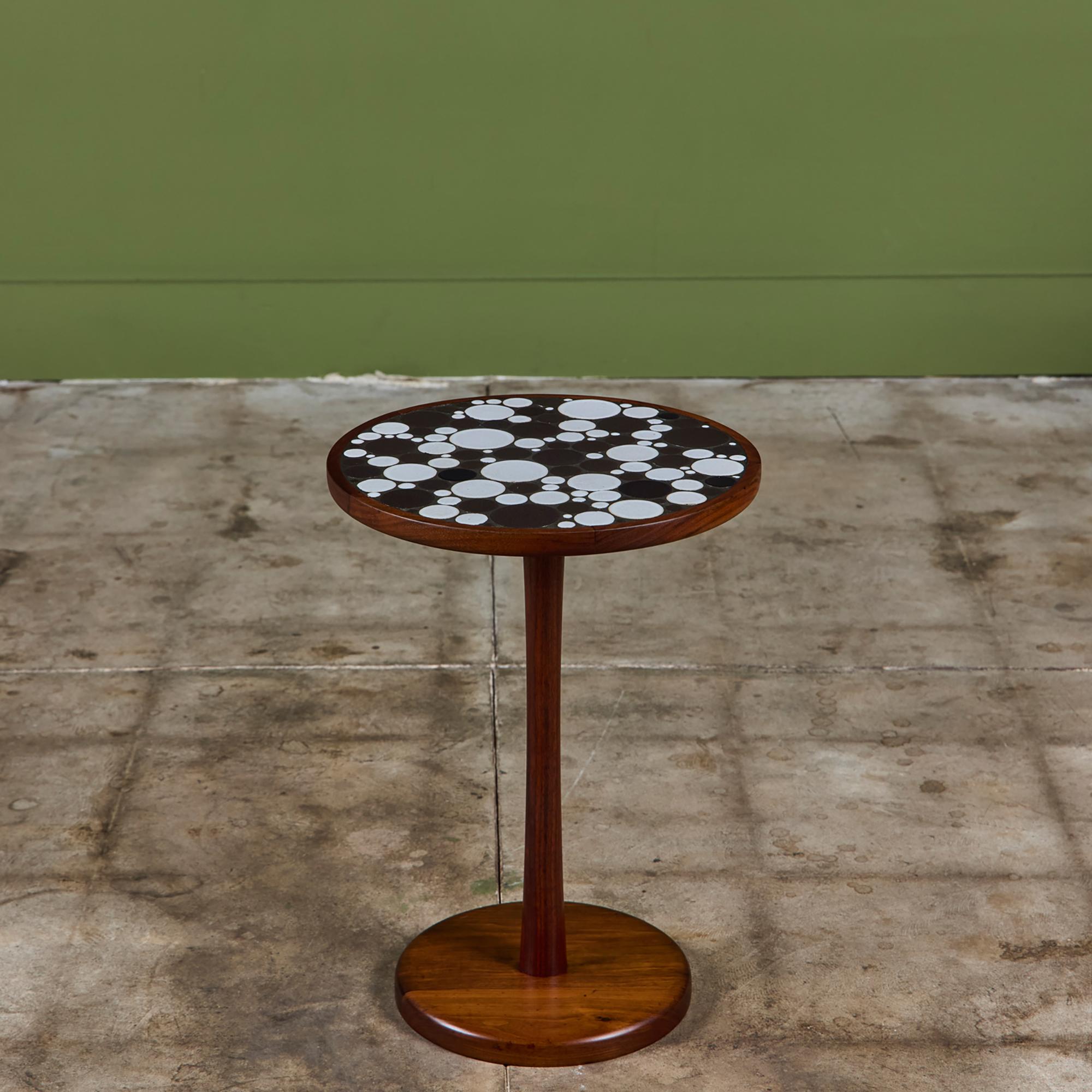 Round side table by Gordon & Jane Martz. The table top is inlaid with ceramic coin tiles in a black and white matte glaze. The frame, base and pedestal of the table are all solid walnut.

Dimensions
13.75