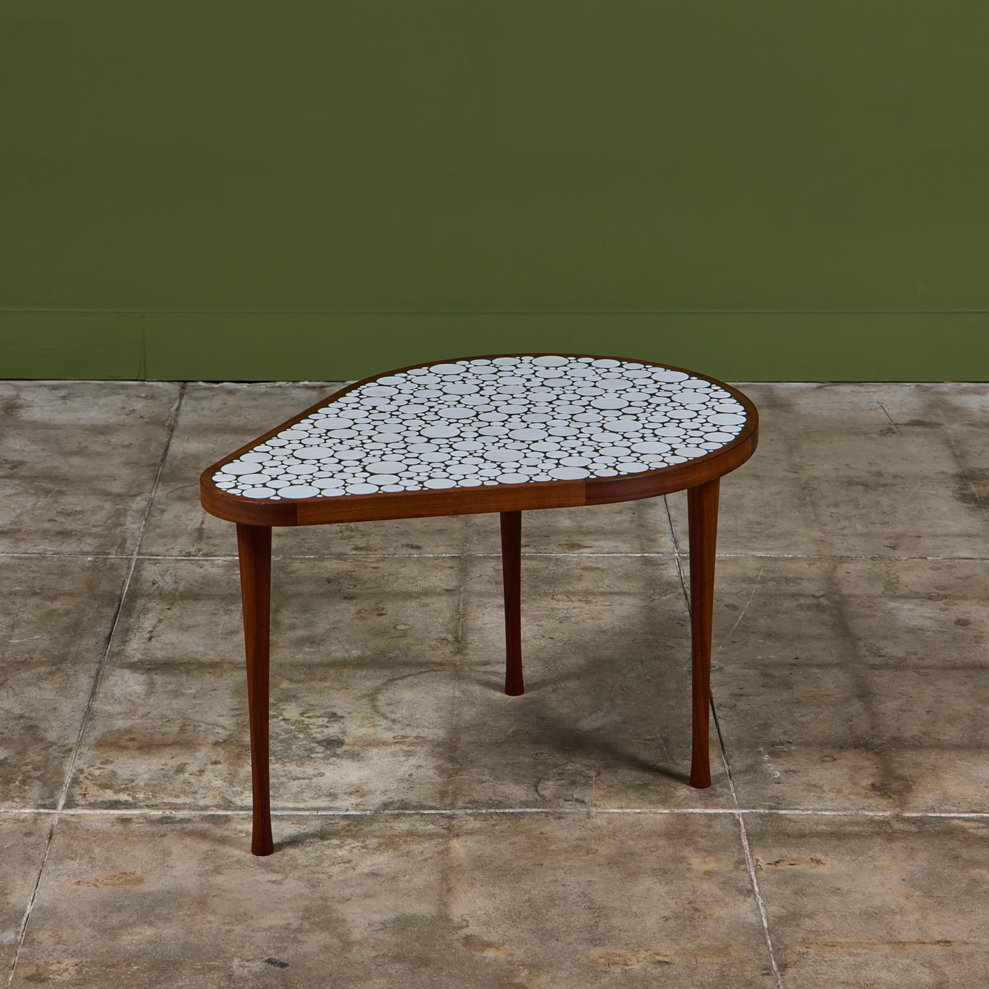 Teardrop side table by Gordon & Jane Martz. The table top is inlaid with white ceramic coin tiles. The frame of the table is solid walnut.

Dimensions
23.5