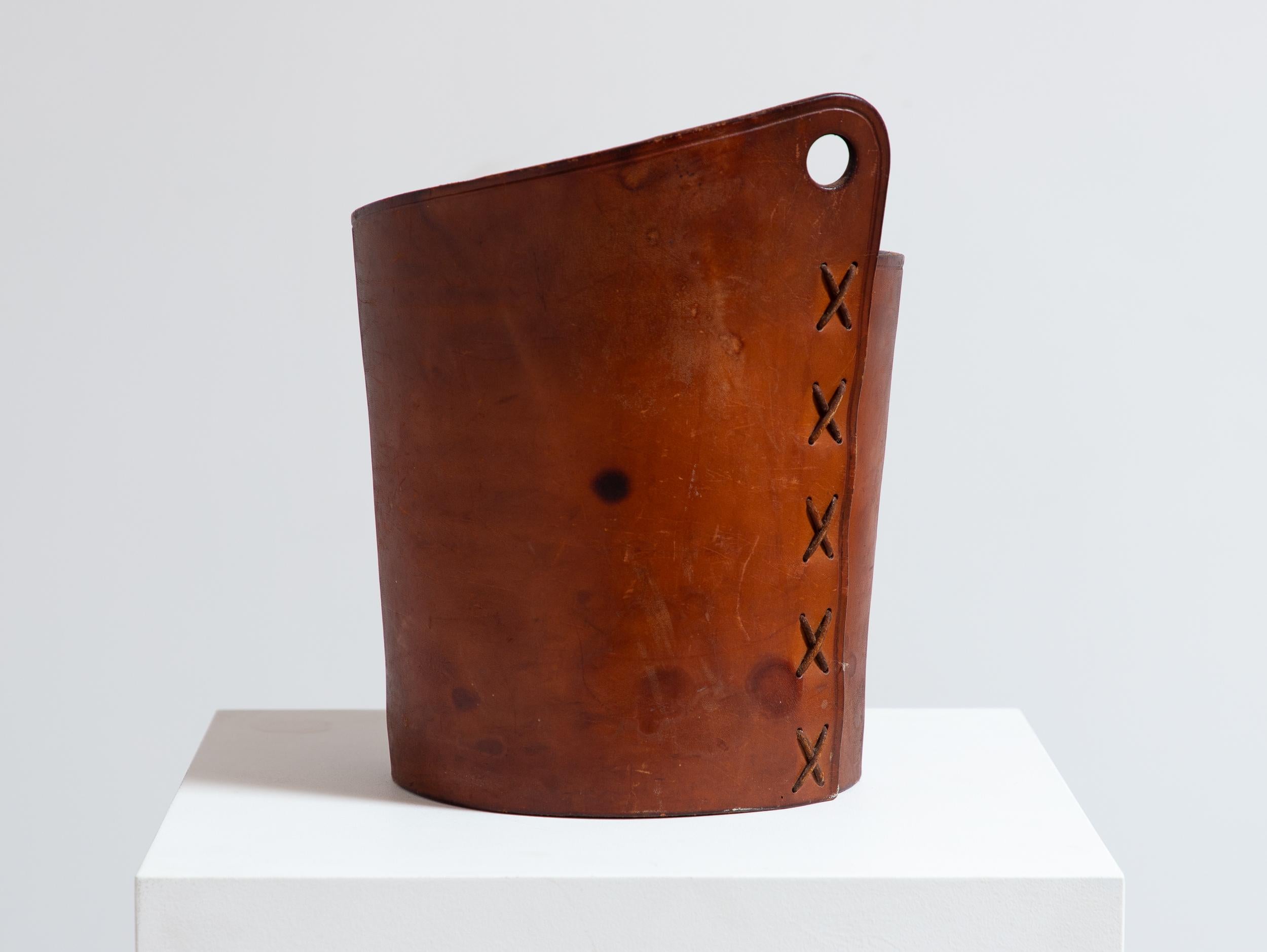 Cestino in pelle unico nel suo genere, progettato da Gordon Keeler, un rinomato artigiano del New Hampshire. Realizzato in pelle di cuoio cognac patinata, il cestino presenta un dettaglio in pelle intrecciata e un design a buco di serratura per