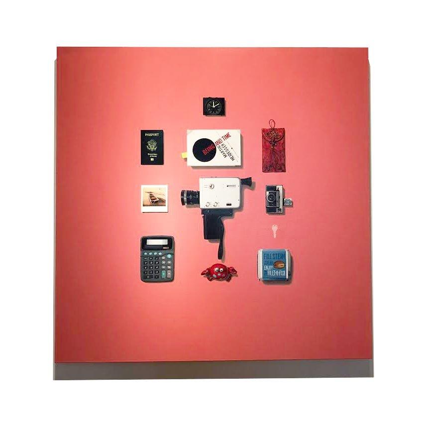 Being and Time by Gordon Lee features a collection of painted found objects arranged on a salmon colored background. Named after the book by famous philosopher Martin Heidegger, Lee creates unlikely conversations between everyday items. Using