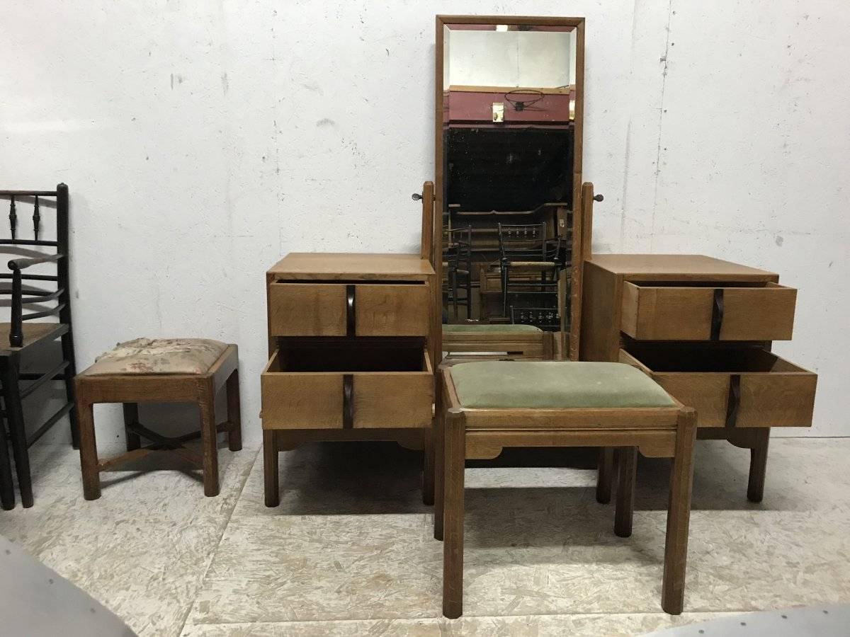 Sir Gordon Russell, (British, 1892-1980). An oak Arts & Crafts Cotswold School oak dressing table and matching stool. The dressing table with a swivel central bevelled mirror with quality brass swivel ends, flanked by four ceder lined drawers that