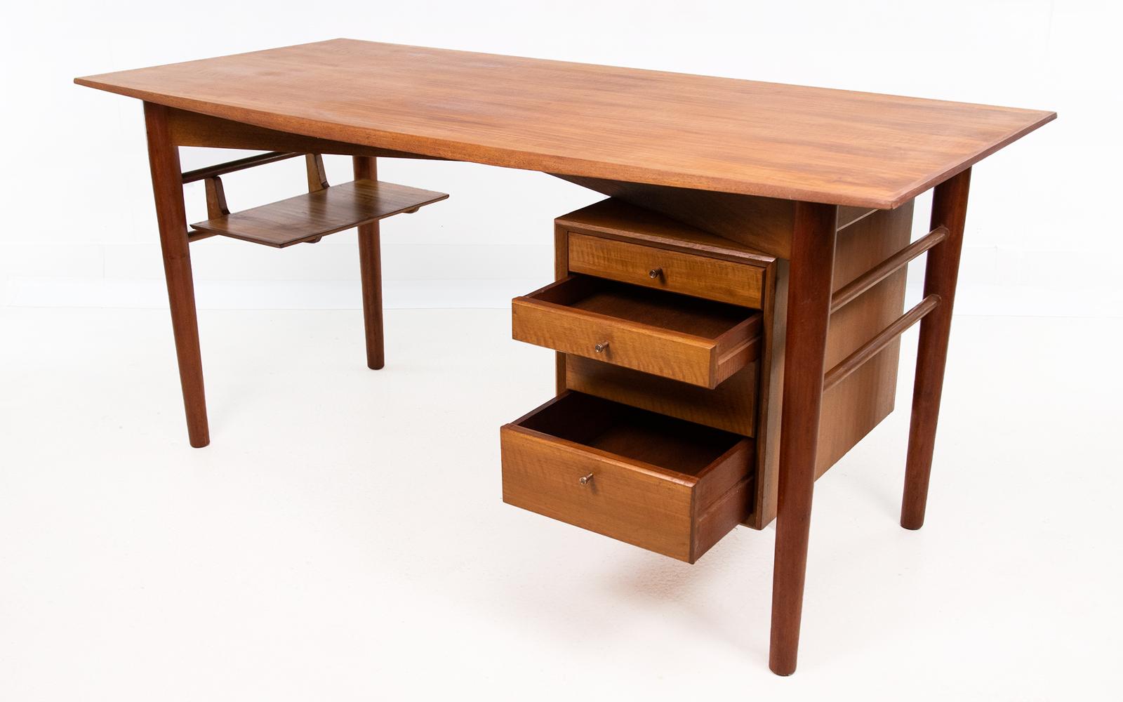 Gordon Russell desk

Mid 20th century walnut and mahogany studio desk, the rectangular top above a floating bank of drawers opposed by an open shelf, raised upon tapering cylindrical legs.

Designed by Gordon Russell and sold through Heal's of