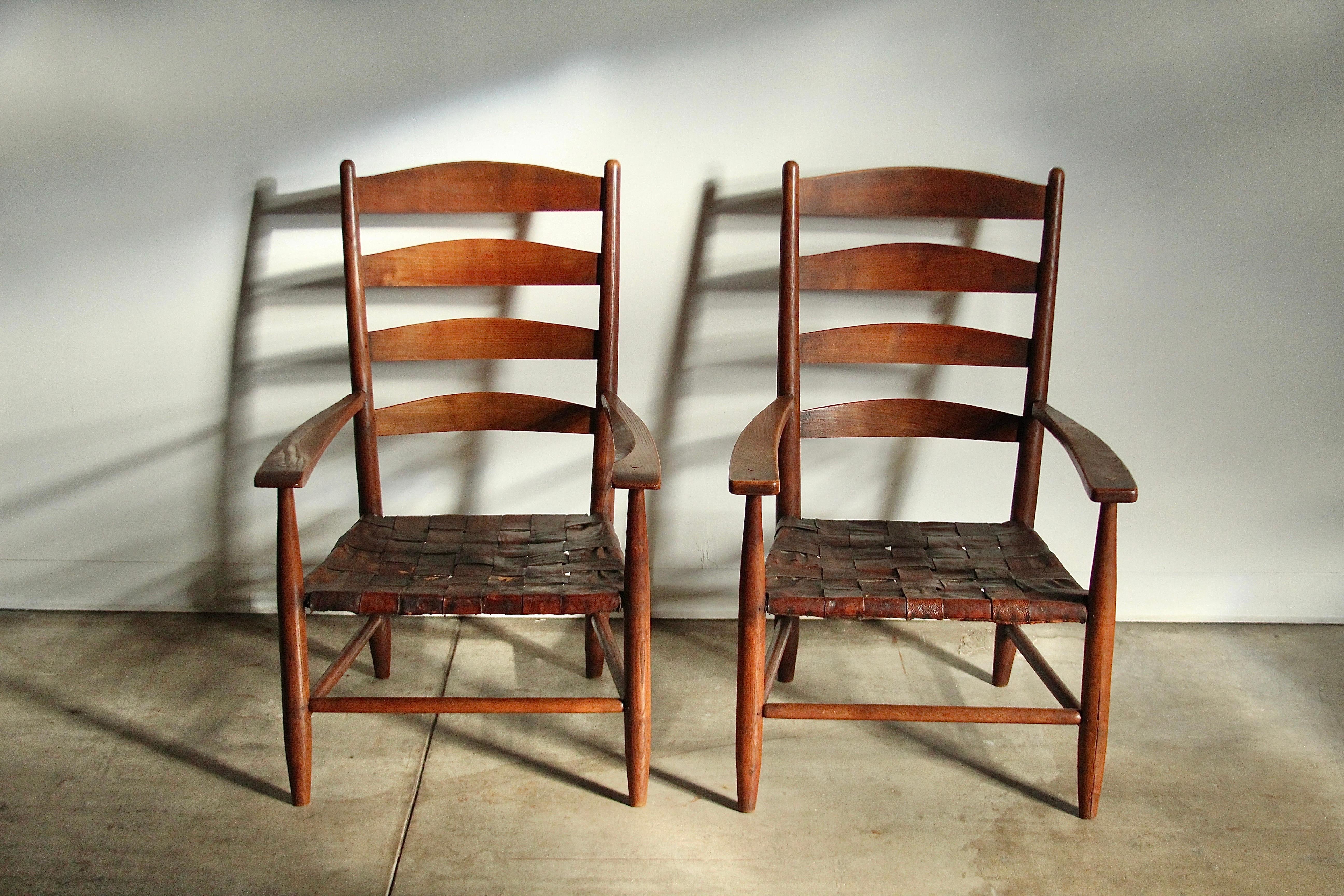 A true pair of artifacts! This pair of large Shaker style, loungey, arm chairs was designed and built by Gordon Russell around 1904 in Broadway, England. The chairs feature incredible, hand built, peg construction, and are crafted with the highest