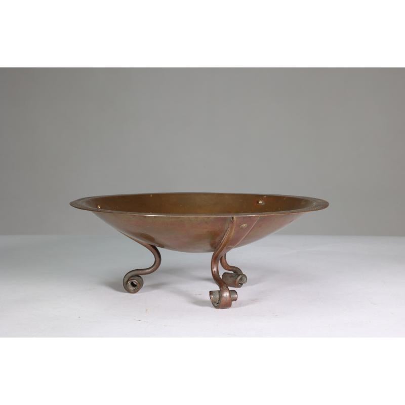 Gordon Russell Lygon Works Design No. 174. A rare Arts and Crafts Cotswold School patinated brass bowl with chased decoration to the rim and three tightly scrolled forged feet that are riveted to the bowl. The design, No. 174, dates to 1924 and is