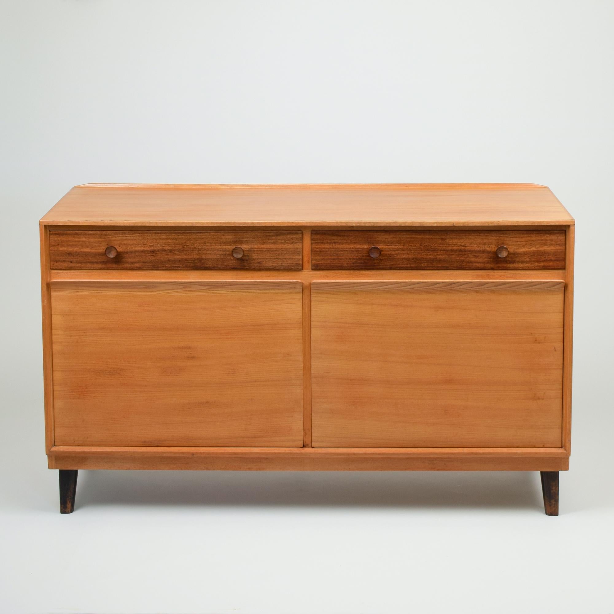 Richard Drew Russell (designer), 1958
Gordon Russell, UK (manufacturer)
Sideboard
Bombay rosewood and Japanese elm
Two drawers above cupboard with pull-down doors and adjustable shelves
Manufacturer's metal label to rear and supplier's plastic