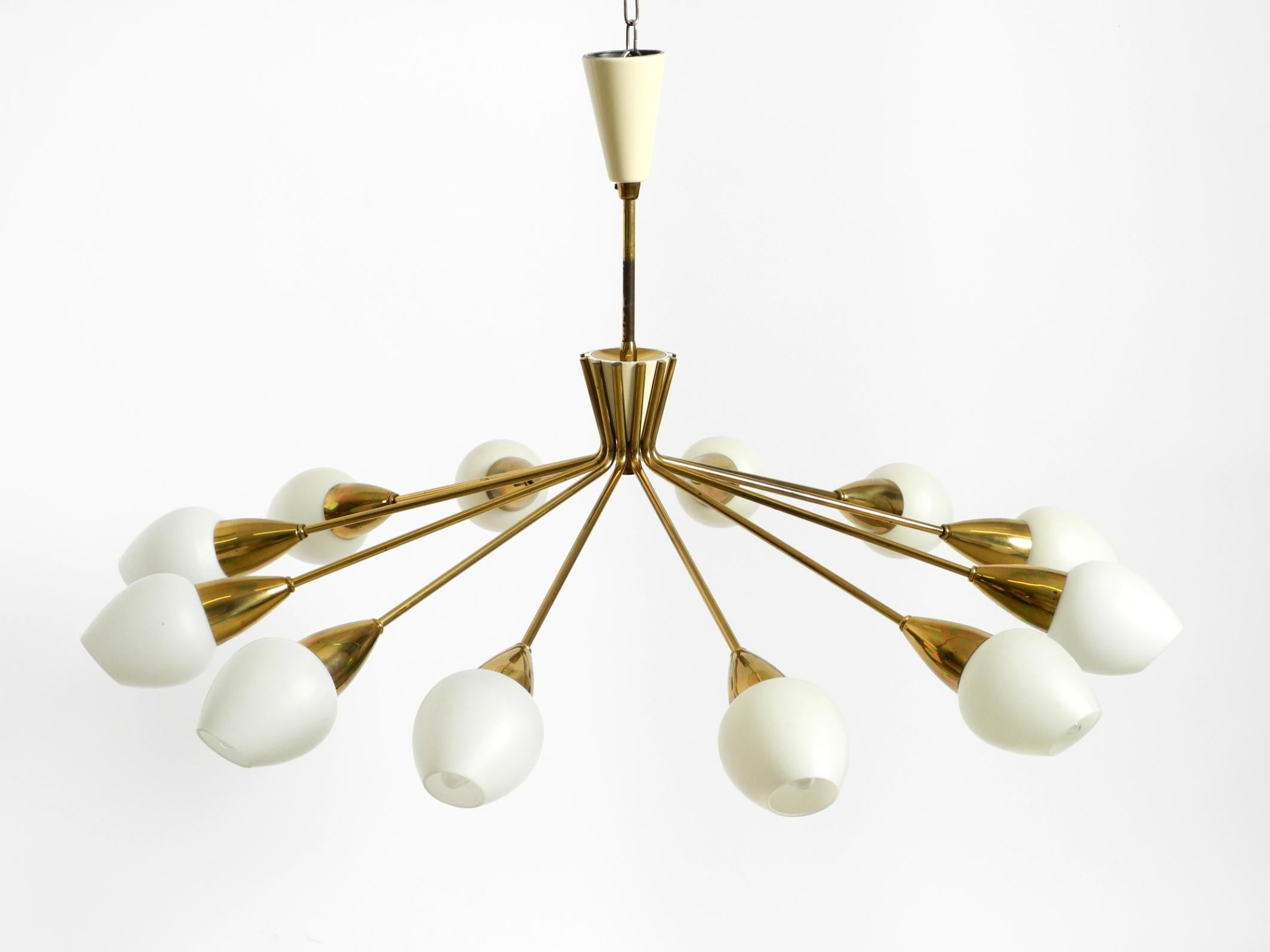 Magnifique, rare, grand lustre en laiton du milieu du siècle à 12 branches avec des abat-jours en verre opale.
Une lampe de très haute qualité avec de nombreux détails.
Magnifique design/One des années 1950. L'ensemble du cadre est en laiton.
Très