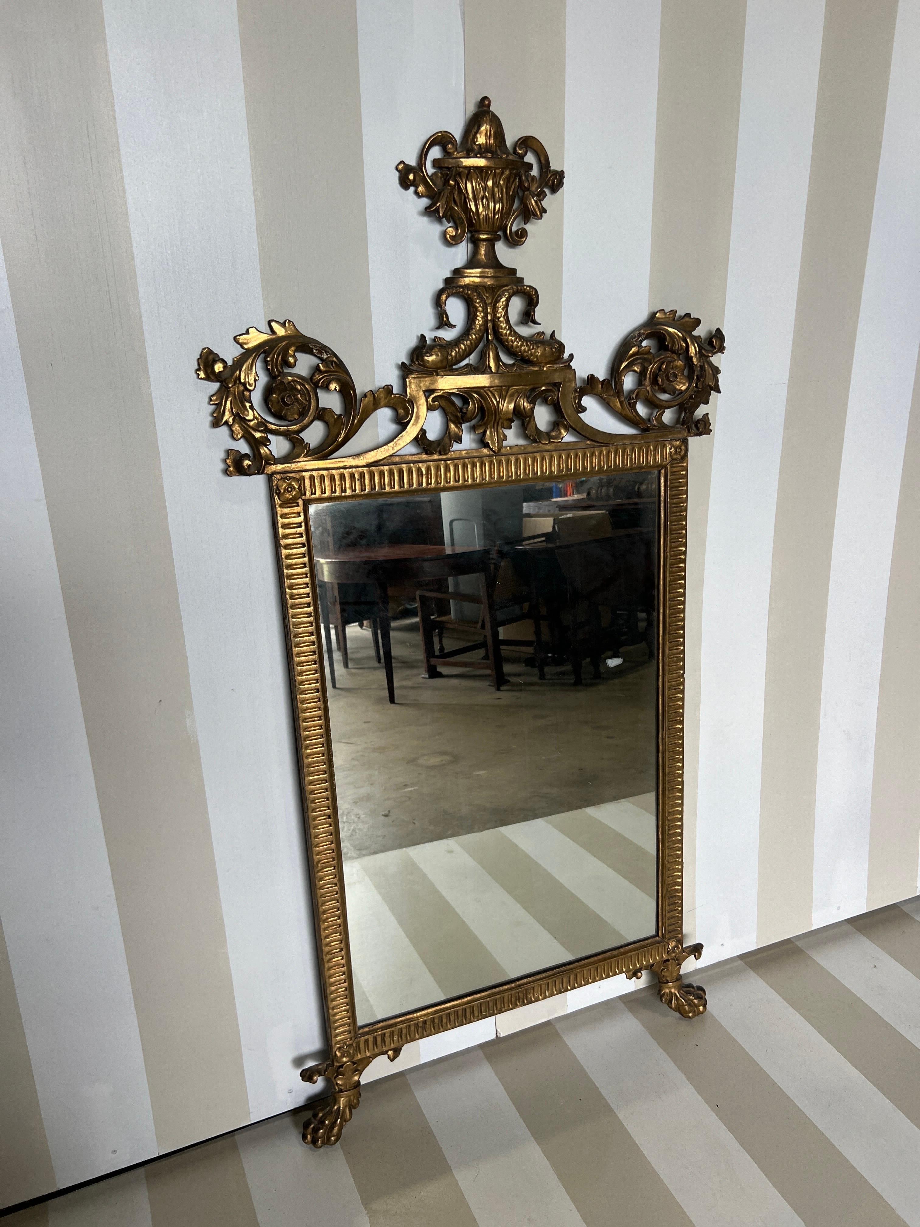 Splendida specchiera neoclassica italiana della fine del XVIII-inizio del XIX secolo in legno dorato con urne e delfini. Con una dimensione di 64,5 x 34 pollici, questo specchio ha una grande scala e profondità. Ottimo colore - ricco legno dorato