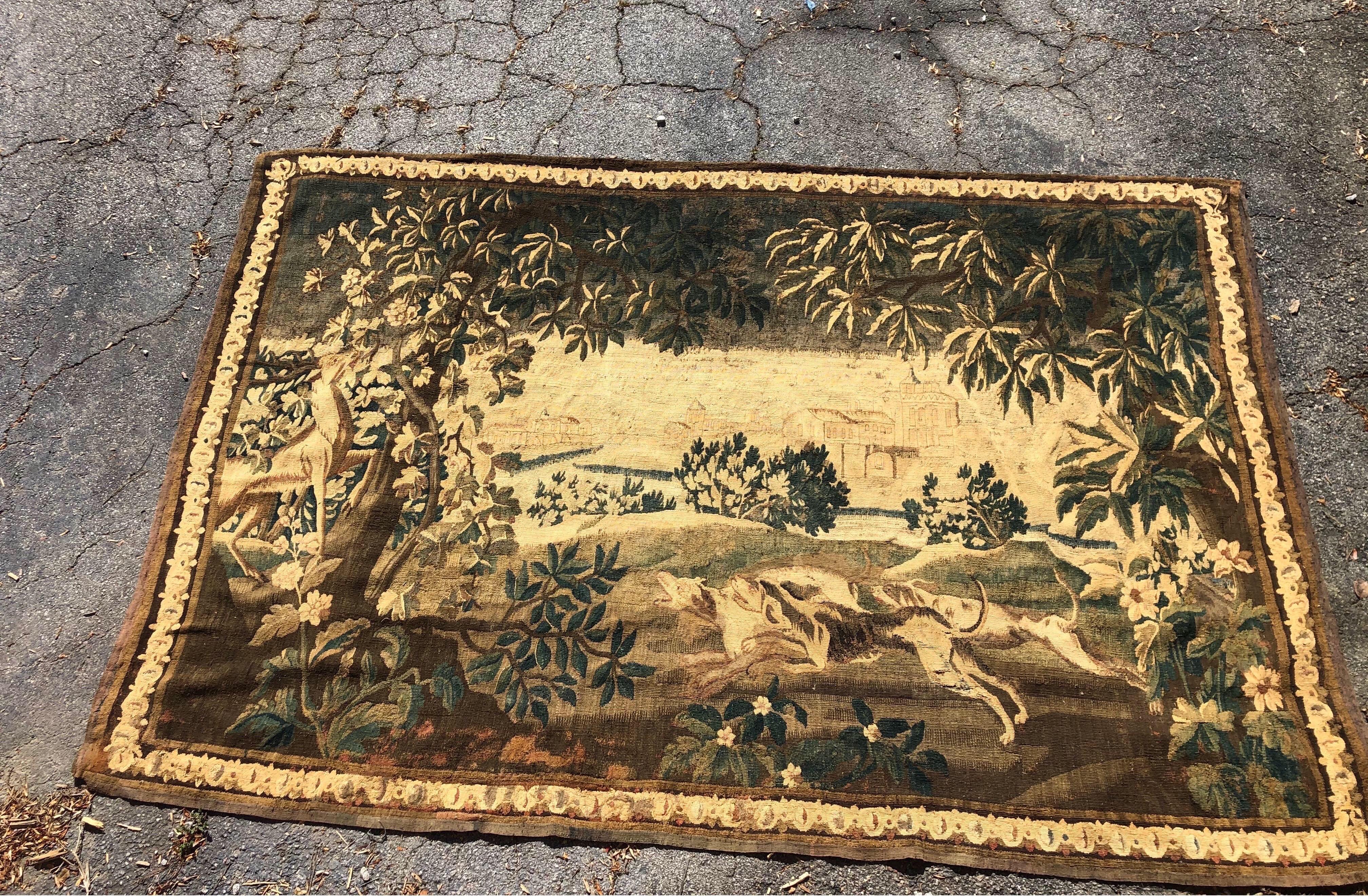 Gorgeous 18th century French Aubusson tapestry of 2 dogs hunting a stag. Incredible quality and size. This tapestry is centered around two dogs hunting a stag in the forefront with a village visible in the distance, all framed in its original,