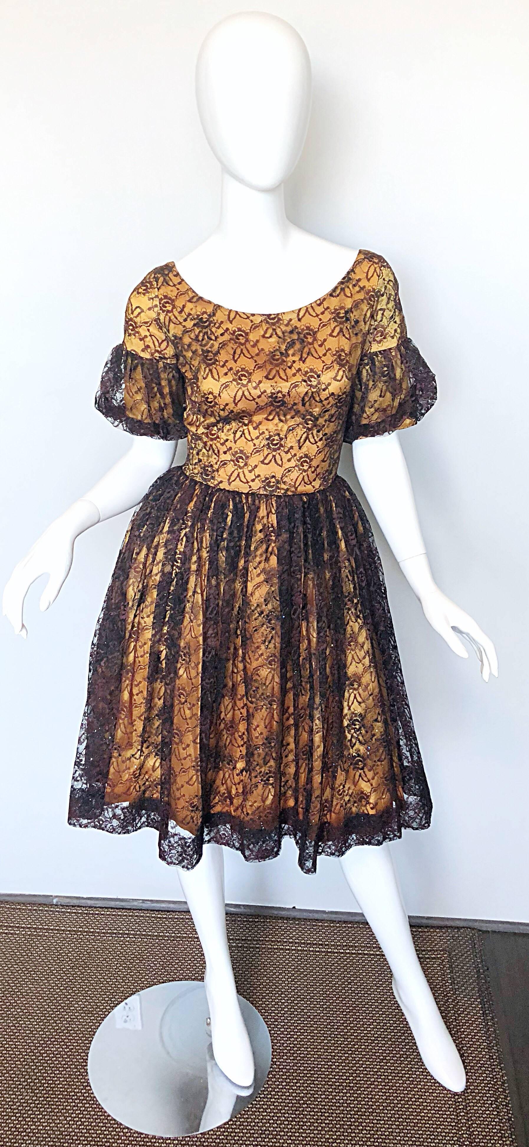 Gorgeous 1950s black and gold silk lace fit n' flare cocktail dress! Features luxurious black French lace with a golden satin underlay, with sparkles of colorful glitter sporadically thorughout. Pretty flounced sleeves. Fitted bodice with a