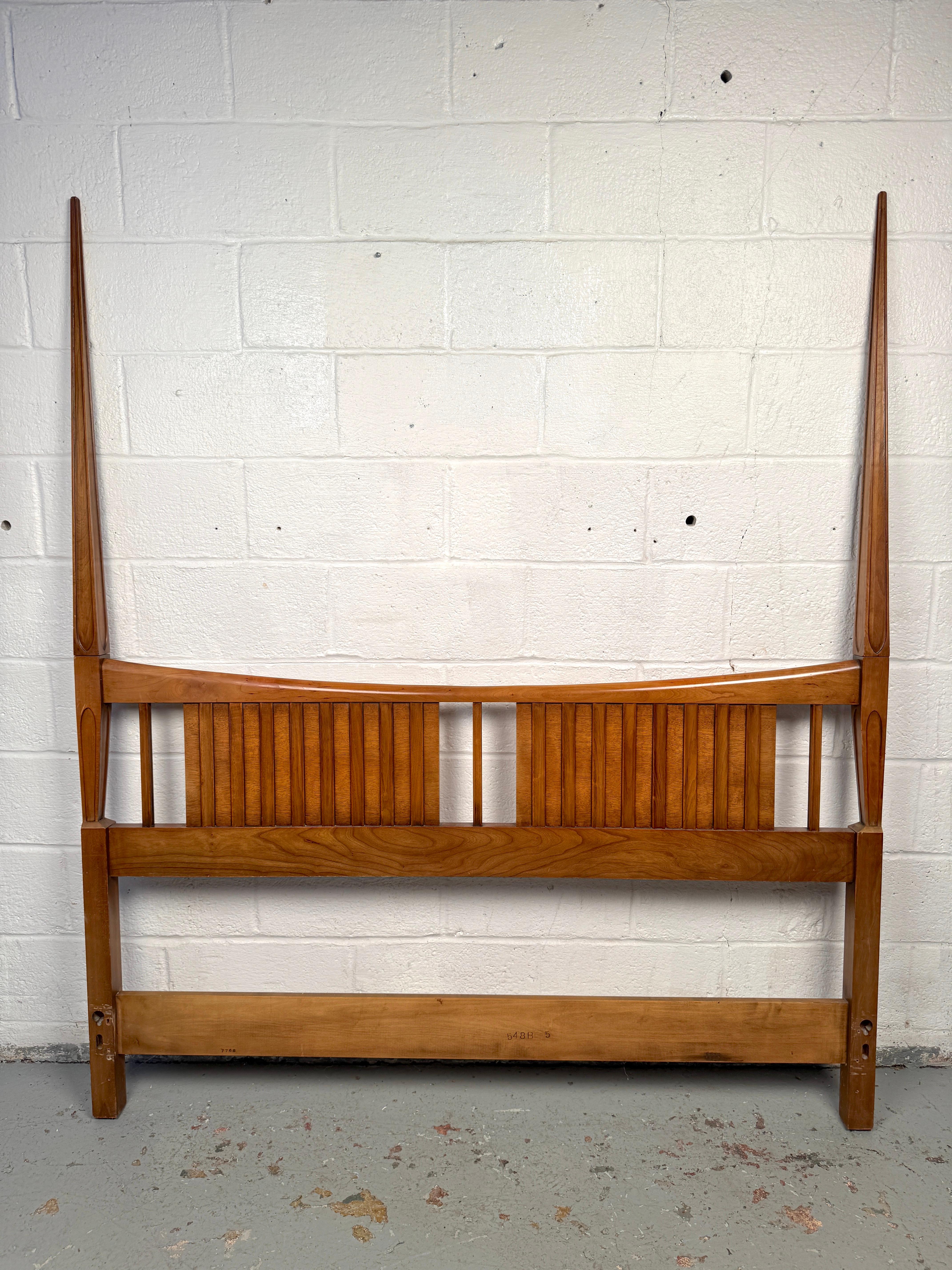 Striking mid-century headboard by John Widdicomb, distinguished by its two tall, sculptural points that give the piece a bold architectural presence. Crafted in fine wood with a warm finish, it balances modern elegance with dramatic form. A standout