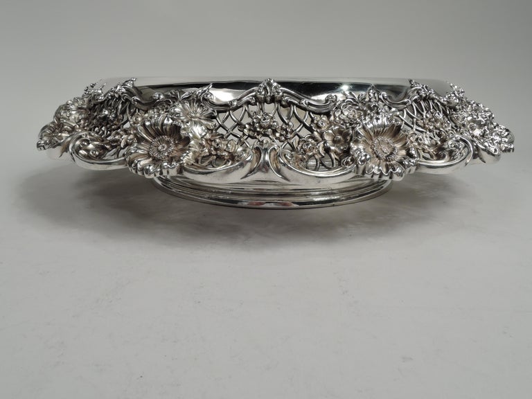 Gorgeous turn-of-the-century sterling silver bowl bowl. Made by Graff, Washbourne & Dunn in New York. Round and solid well and turned-down rim with blossom bunches and scattered flower heads on open lattice ground between leaf and scroll borders.