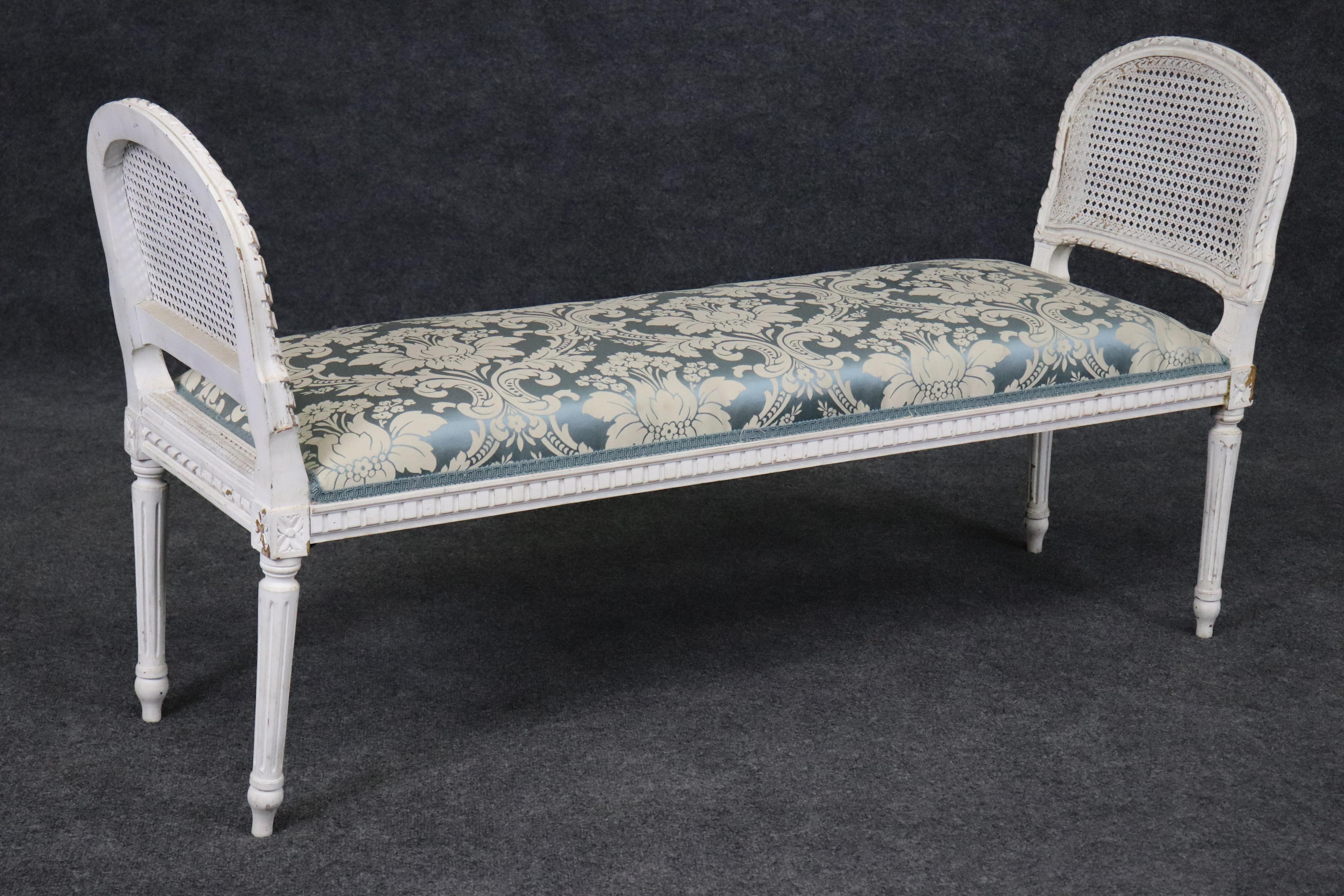 This is a gorgeous bench made of walnut and cane and we believe silk damask upholstery. The bench is perfect for a window, the end of a bed in a bedroom or anywhere else you can think of. The finish has some paint losses and minor signs of chips and