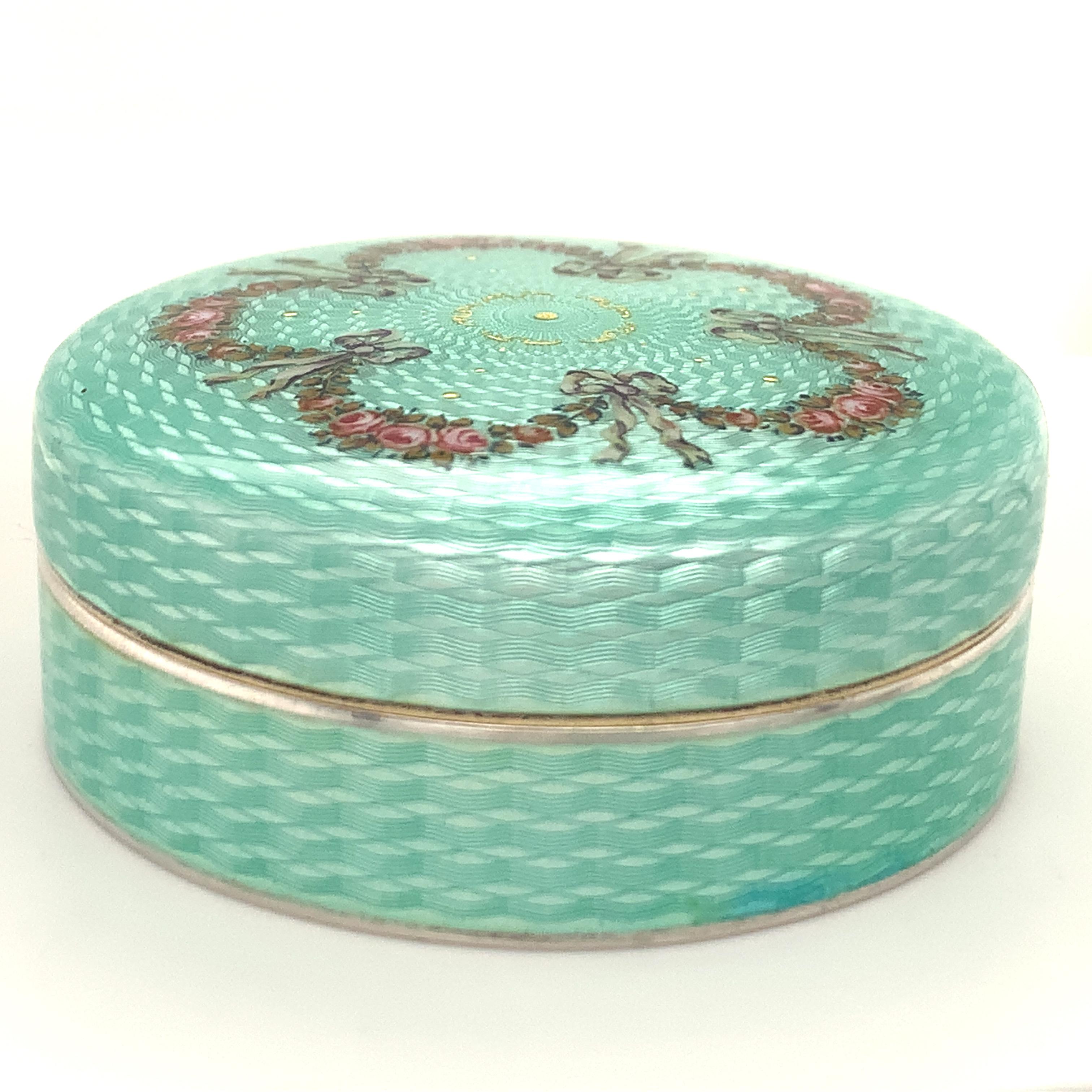 Exquisite guilloche enamel round covered box.  A luminous sea green color, with great brilliance and depth. Top and sides entirely covered with enamel, decorated with garlands of delicate pink and green rosettes and leaves, with gold leaf detailing.